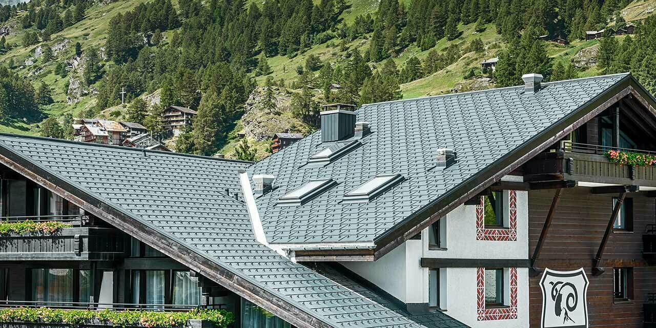 Hotel Alpenhof v Zermattu s Matterhornem v pozadí, balkony s tmavou dřevěnou fasádou a hliníkovou střechou PREFA v antracitové barvě