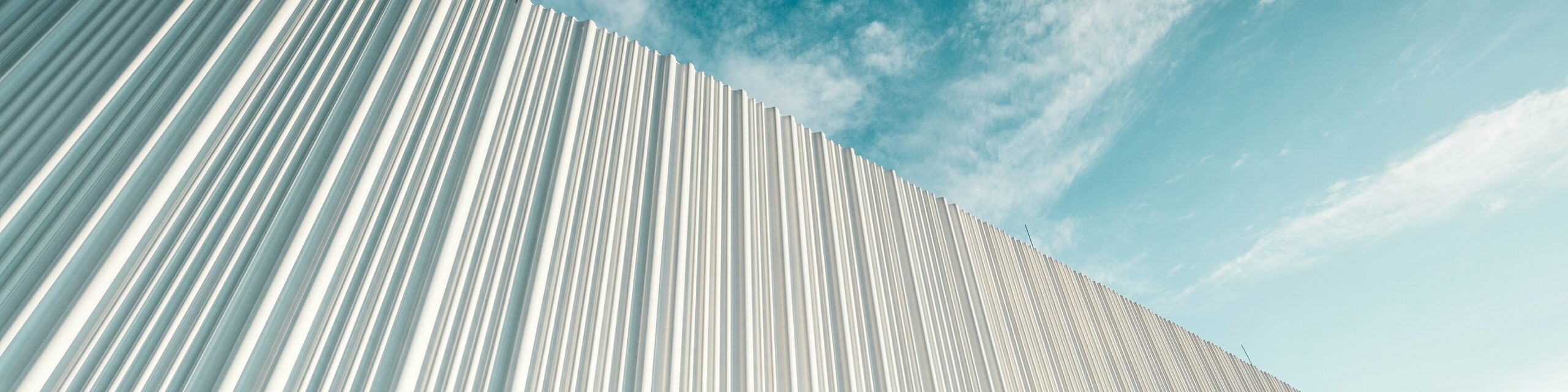 Úchvatná architektura s bílou hliníkovou fasádou PREFA v obchodním parku Walter u Vídně. Fasáda, vyrobená z na míru vyrobených lisovaných profilů, vytváří svým plynulým, vlnitým tvarem podmanivou hru světla a stínu. Tři různé tvary profilů zajišťují výjimečný pocit hloubky a propůjčují budově stylově čistý, ale zároveň dynamický vzhled. Povětrnostním vlivům odolný povrch PREFA spojuje moderní estetiku s funkční dokonalostí – skutečný vrchol současného designu fasád, který prezentuje architektonickou kvalitu a technickou propracovanost.