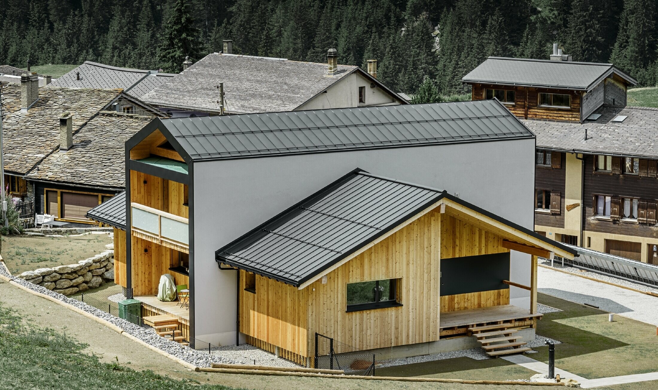 Tento rodinný dům vypadá, jako by byly 2 domy umístěny nad sebou pod úhlem 90°. Střecha je pokryta svitkových plechem PREFALZ v barvě P.10 černé. Fasáda je částečně obložena dřevem.