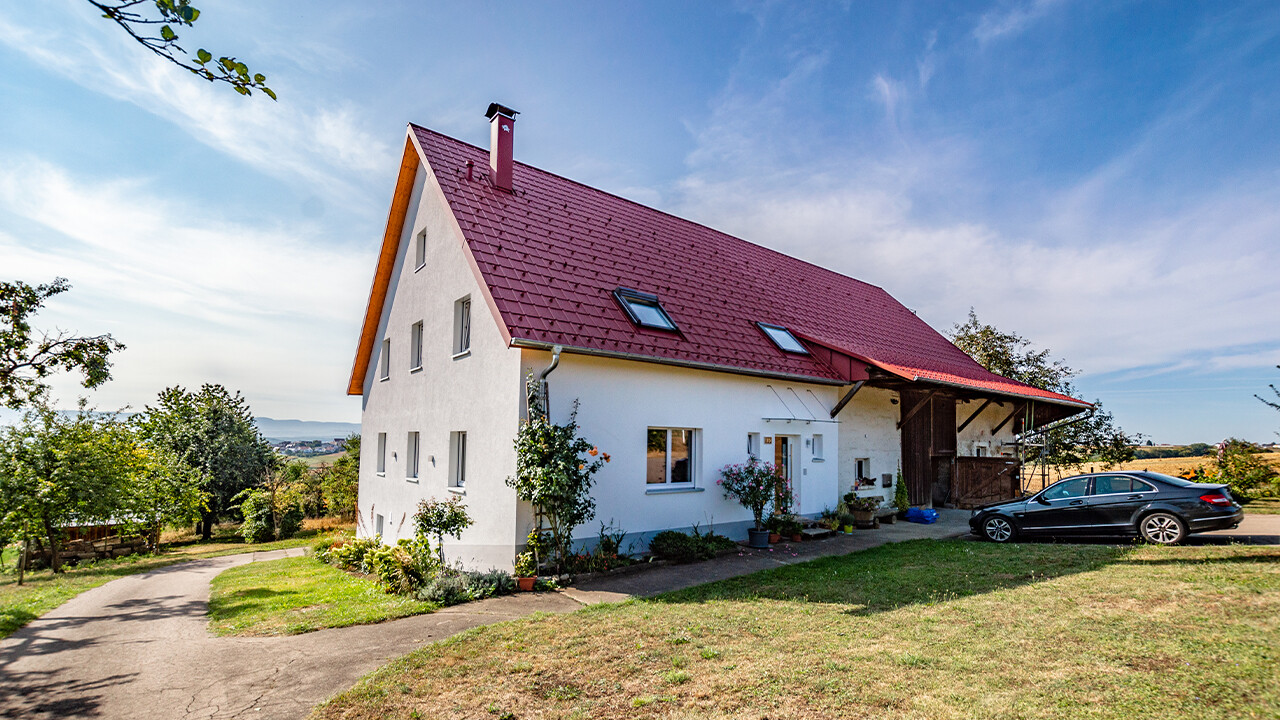 Malé venkovské stavení s pěkně zrekonstruovanou střechou z falcovaných tašek v tmavě červené barvě.