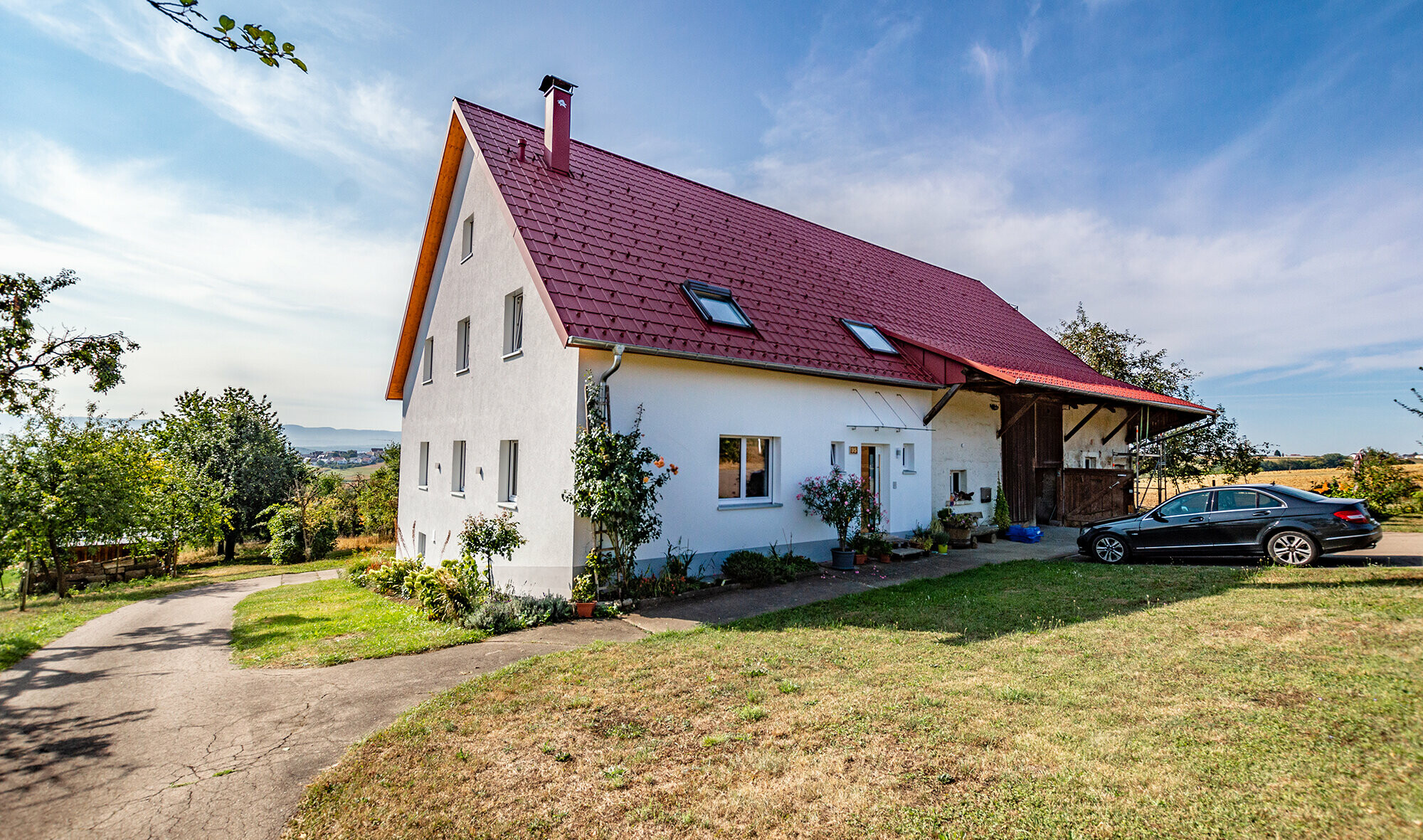 Malé venkovské stavení s pěkně zrekonstruovanou střechou z falcovaných tašek v tmavě červené barvě.