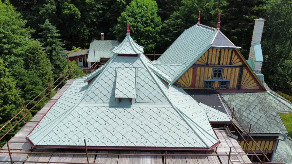 Záběr z dronu na historickou vilu od legendárního architekta Dušana Jurkoviče v Novém Městě nad Metují, která prochází citlivou rekonstrukcí s PREFA falcovanými šablonami 29 x 29 v barvě na zakázku - opálově zelené.
