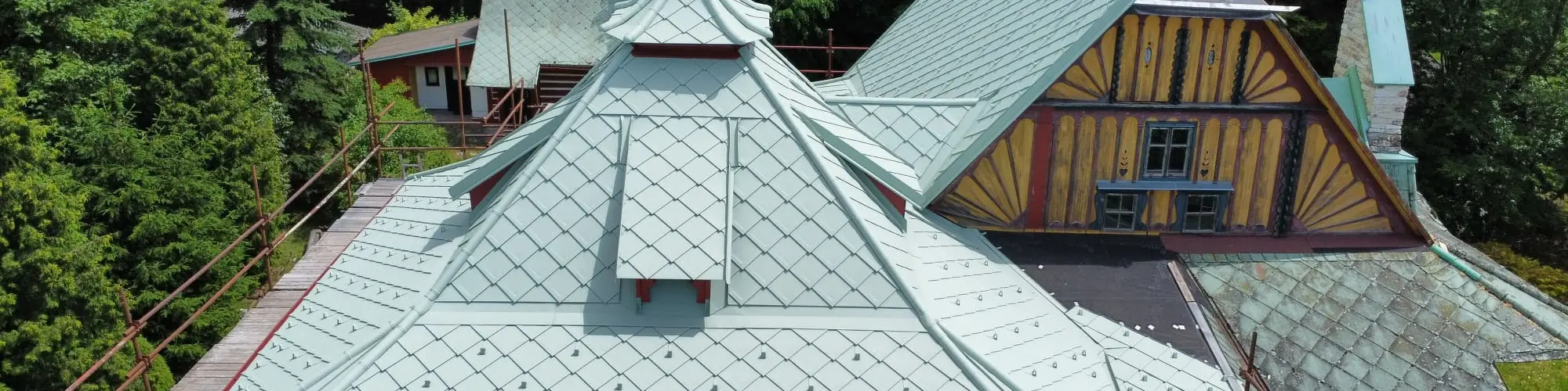 Záběr z dronu na historickou vilu od legendárního architekta Dušana Jurkoviče v Novém Městě nad Metují, která prochází citlivou rekonstrukcí s PREFA falcovanými šablonami 29 x 29 v barvě na zakázku - opálově zelené.