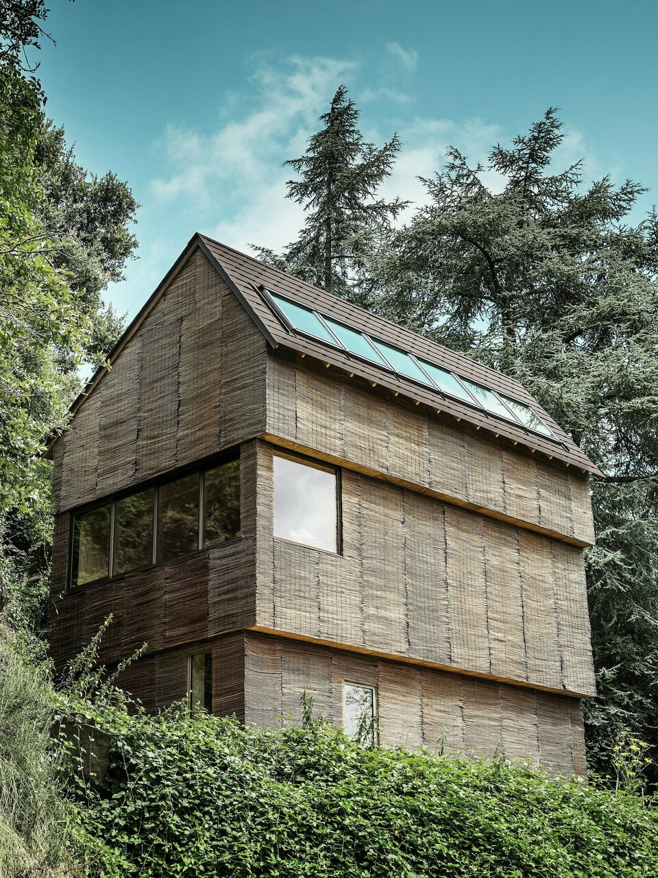 Dům v západní Francii s falcovanými šindeli PREFA v barvě P.10 oříškové na strmém kopci – moderní design s proutěnou fasádou a energeticky úspornou střechou.