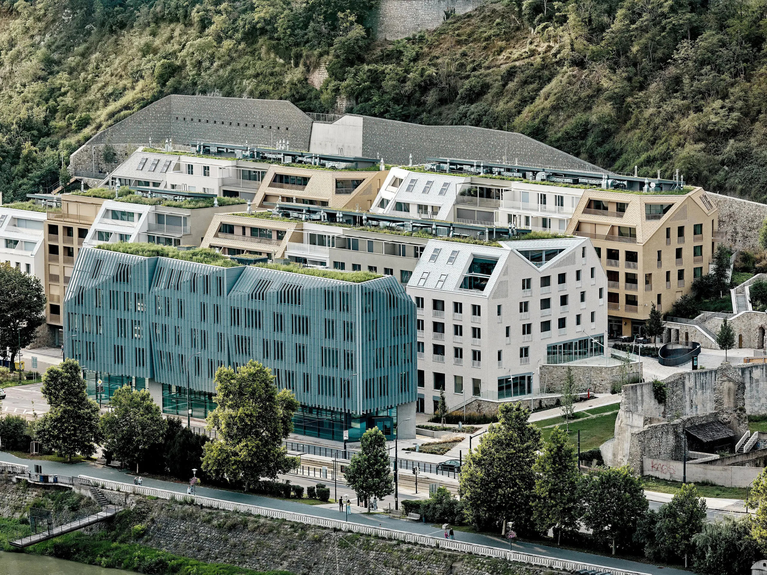 Městská čtvrť Vydrica v Bratislavě, ležící na břehu Dunaje, vytváří působivý celkový dojem: Terasovitou architekturu se zelenými střechami, výraznými šikmými střechami a čistými liniemi definují hliníkové střešní šindele PREFA v odstínech prefa bílá, písková a bronzová. Rozmanitá střešní krajina s integrovanými střešními okny a precizními detaily poutá pozornost celým komplexem. Hliník PREFA umožňuje jemné, komplexní tvary a přesvědčuje svou trvanlivostí, nízkou hmotností a extrémní odolností vůči povětrnostním vlivům – ideální pro udržitelné, architektonicky sofistikované městské projekty.