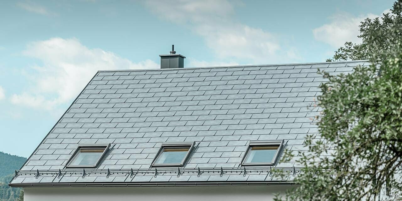 Klasická sedlová střecha pokrytá střešním panelem R.16 se třemi světlíky a systémem pro zadržování sněhu. Fasáda je omítnuta bílou barvou.