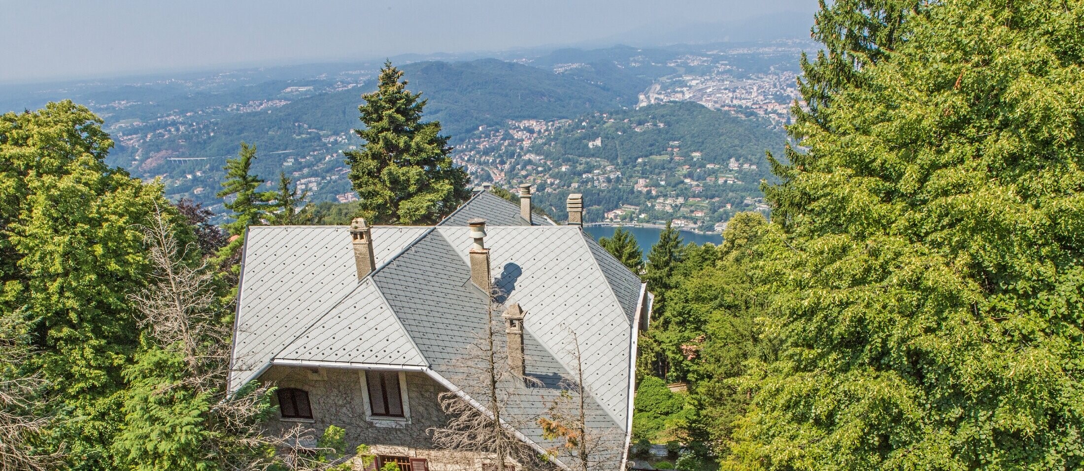 Pohled z ptačí perspektivy na vilu Brunate s členitou střechou pokrytou falcovanou šablonou 29 × 29 v barvě P.10 světle šedé