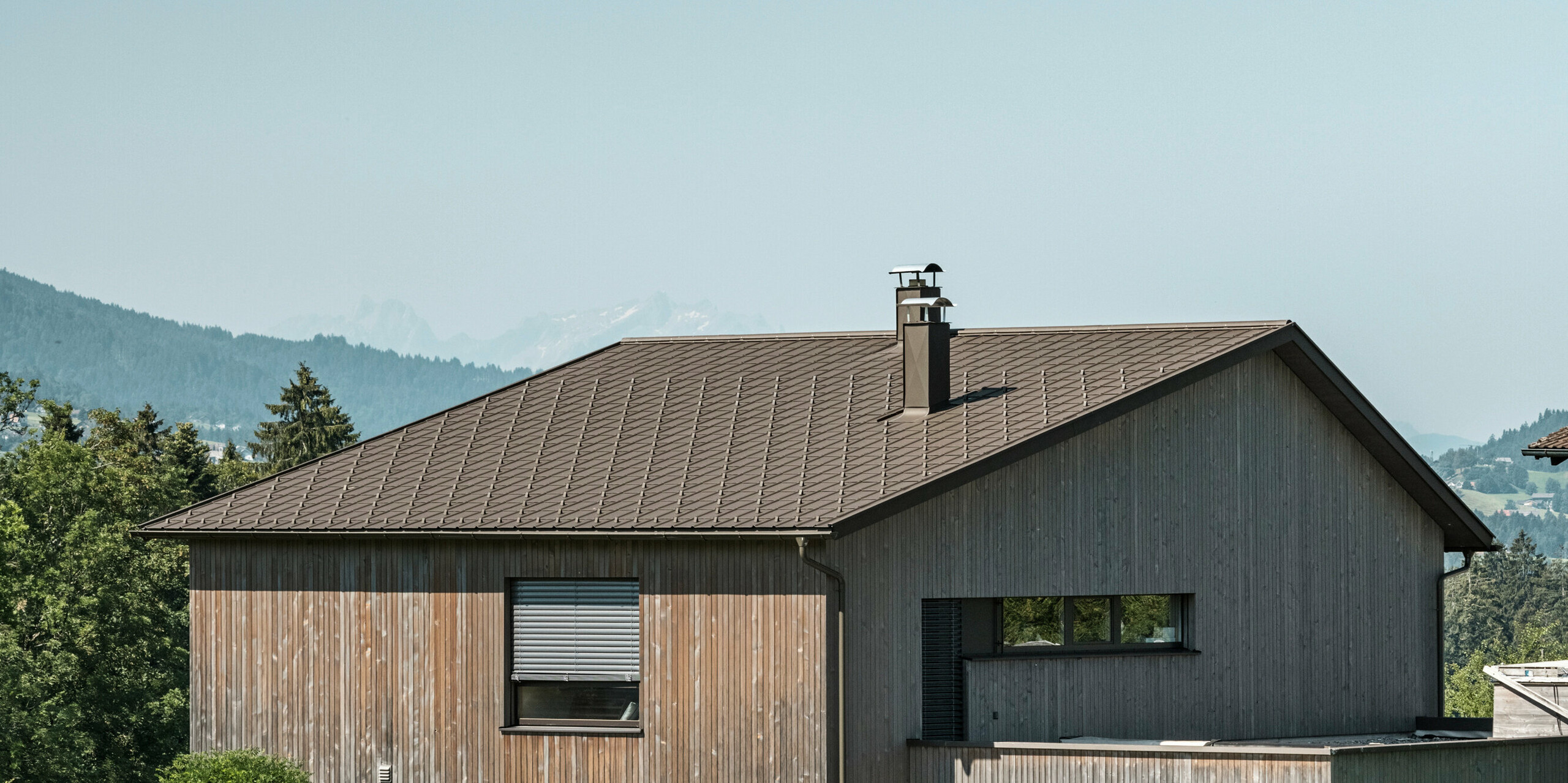 Dřevěná fasáda v kombinaci s hliníkovou střechou působí harmonicky