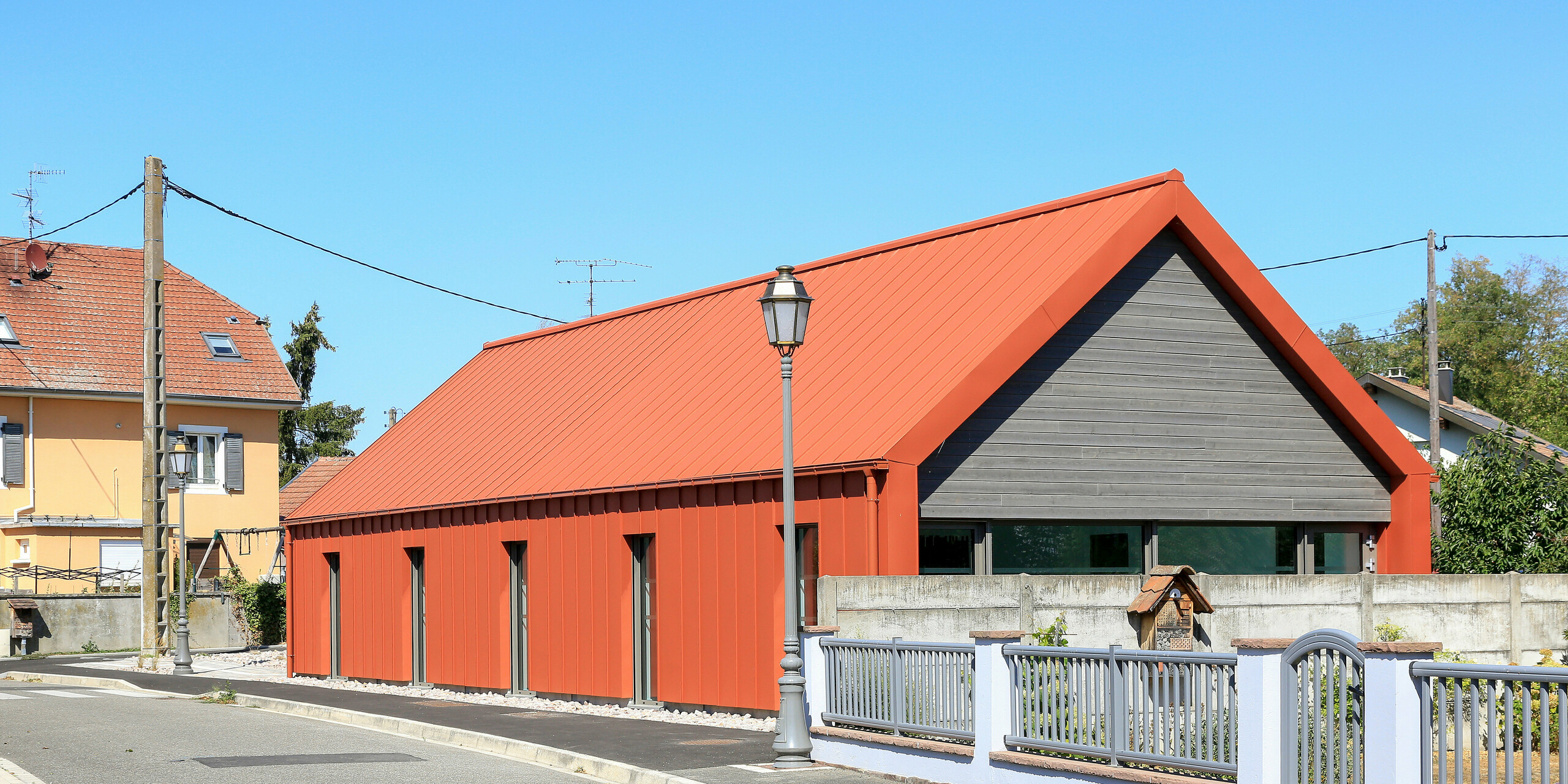 Střecha, fasáda doplněné o hranatý žlab a kruhový svod. Vše v barvě P.10 cihlově červené od PREFA.