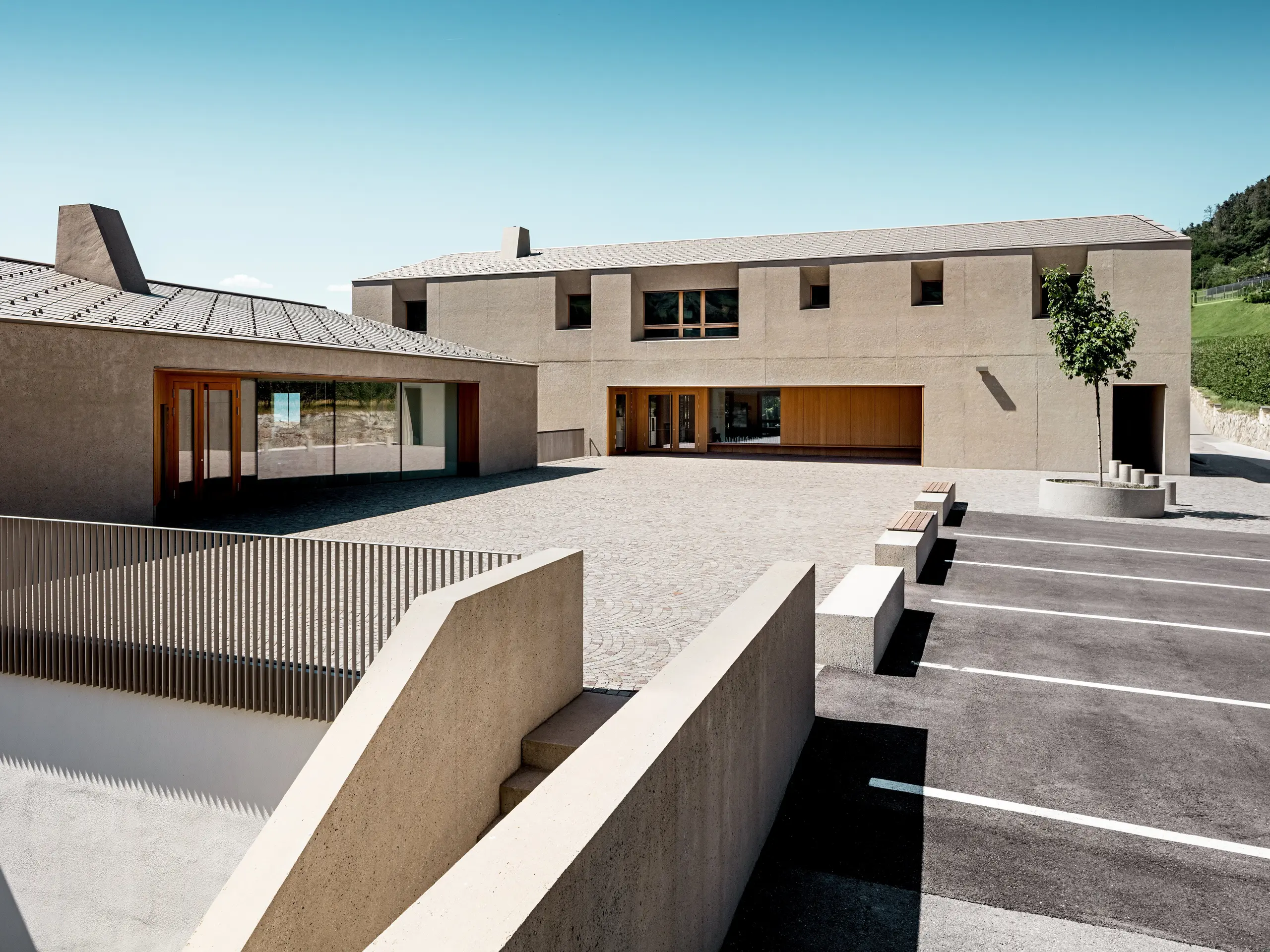 Vzdělávací centrum Riffian v Jižním Tyrolsku kombinuje moderní architekturu s precizním designem střechy. Obě budovy, obložené falcovanými šablonami PREFA 44 x 44 ve tvaru kosočtverce v barvě P.10 bronzové, harmonicky zapadají do krajiny. Odolná hliníková střecha poskytuje spolehlivou ochranu před povětrnostními vlivy a podtrhuje čisté linie školní budovy.