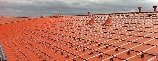 Detailní snímek PREFA hliníkové střechy s optikou pálené tašky-PREFA falcovaná střešní taška v cihlově červené barvě se sněhovými zarážkami