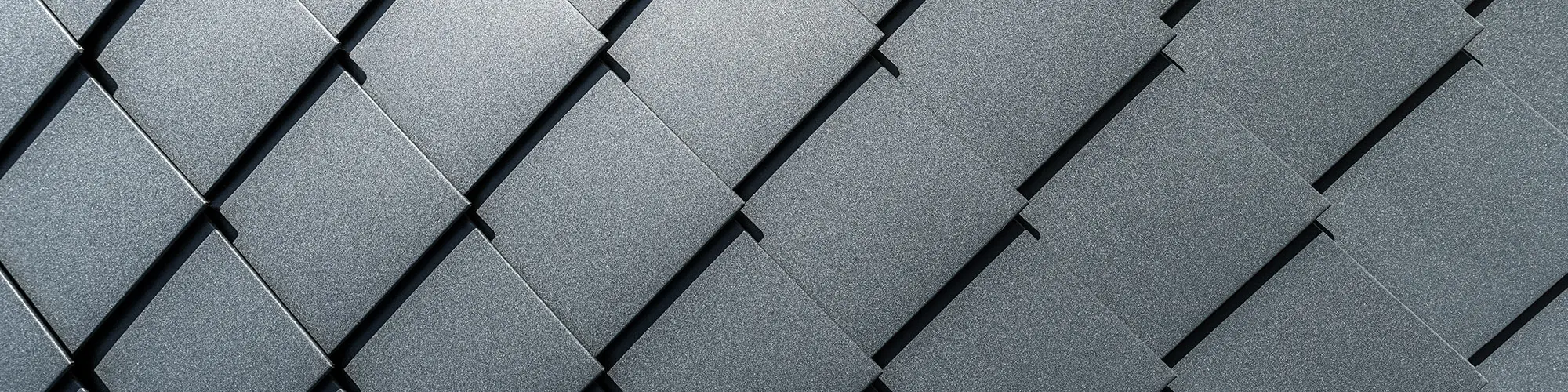 Detailní záběr fasády s precizně položenými hliníkovými fasádními šablonami na fasádě domu v antracitové barvě.