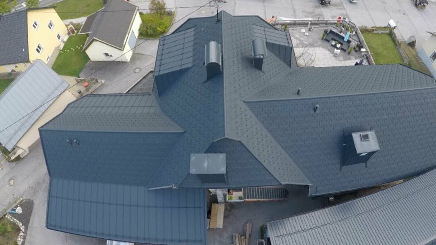 Sanace velké střešní plochy s mnoha detaily - úžlabími, vikýři a komíny. Střecha je pokryta hliníkovými PREFA střešními panely R.16 antracitové barvy.