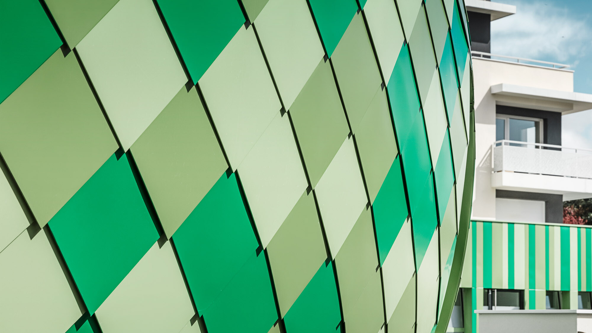 Boční detailní pohled na hliníkový plášť vyrobený z fasádních šablon ve speciálních barvách na zakázku - šedozelená, rezedová zelená a normovaná mátově zelená