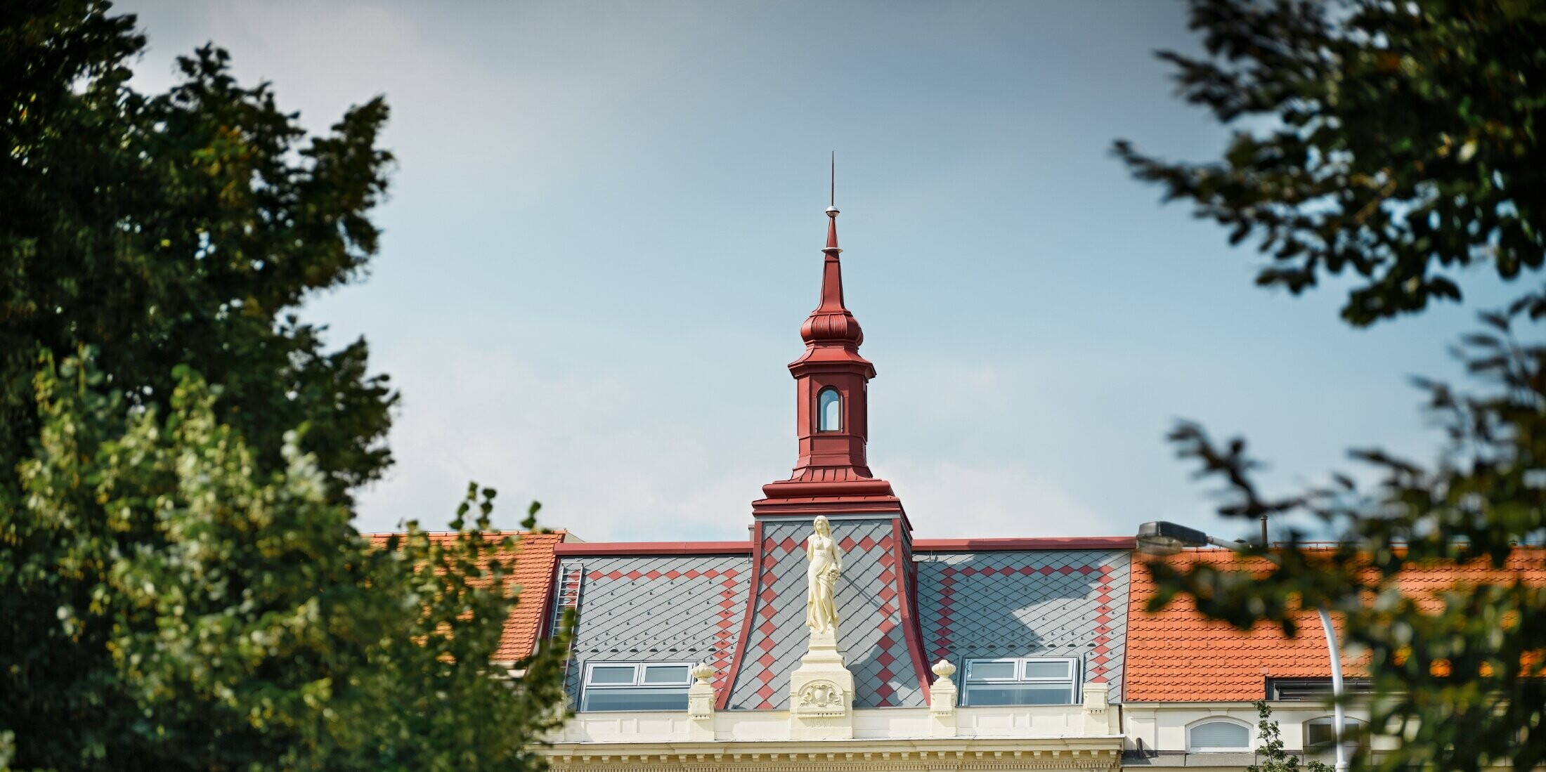 Pohled zdálky na historický bytový dům s krásně zdobenou střechou