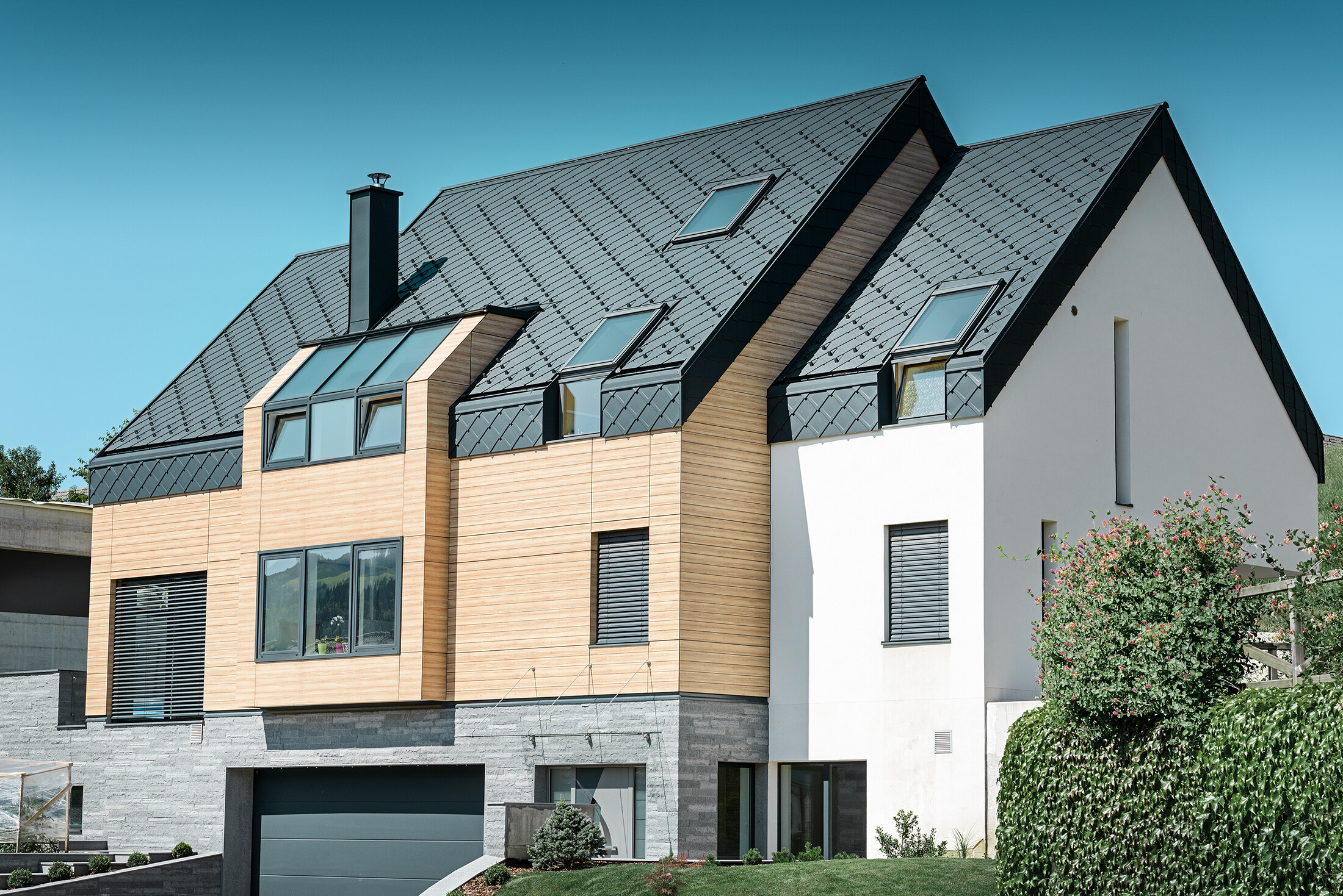 Moderní novostavba, ve které střešní plášť přesahuje přes horní část fasády. Jako střešní krytina byla použita hliníková falcovaná šablona v barvě P.10 antracitové