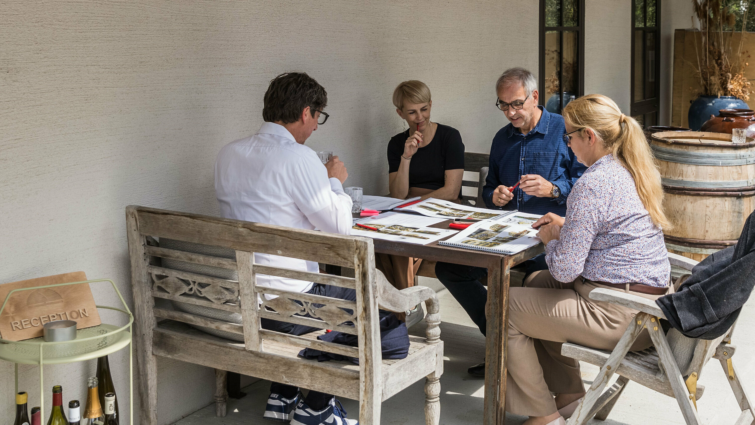 Malá pracovní skupina na expertním dialogu PREFARENZEN 2026 v rezidenci vinaře v regionu Seewinkel v Burgenlandu: Judit Nemere (jednatelka PREFA Maďarsko), Veronika Roll (marketing PREFA Rakousko), Sven Disser (vedoucí rozvoje, Bauwerk) a Wolfgang Croce (Croce & Wir, Graz) diskutují o designové kvalitě předložených architektonických projektů. Důraz je kladen na kreativní využití hliníkových řešení PREFA v současné architektuře. Uvolněná atmosféra podporuje soustředěnou výměnu názorů na inovace, funkčnost a kontext.