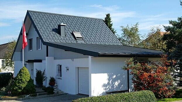 Sanovaný dům se sedlovou střechou a přilehlou garáží. Střecha domu byla pokryta PREFA falcovanými střešními taškami a garáž krytinou Prefalz antracitové barvy. Před domem je stožár se švýcarskou vlajkou. 