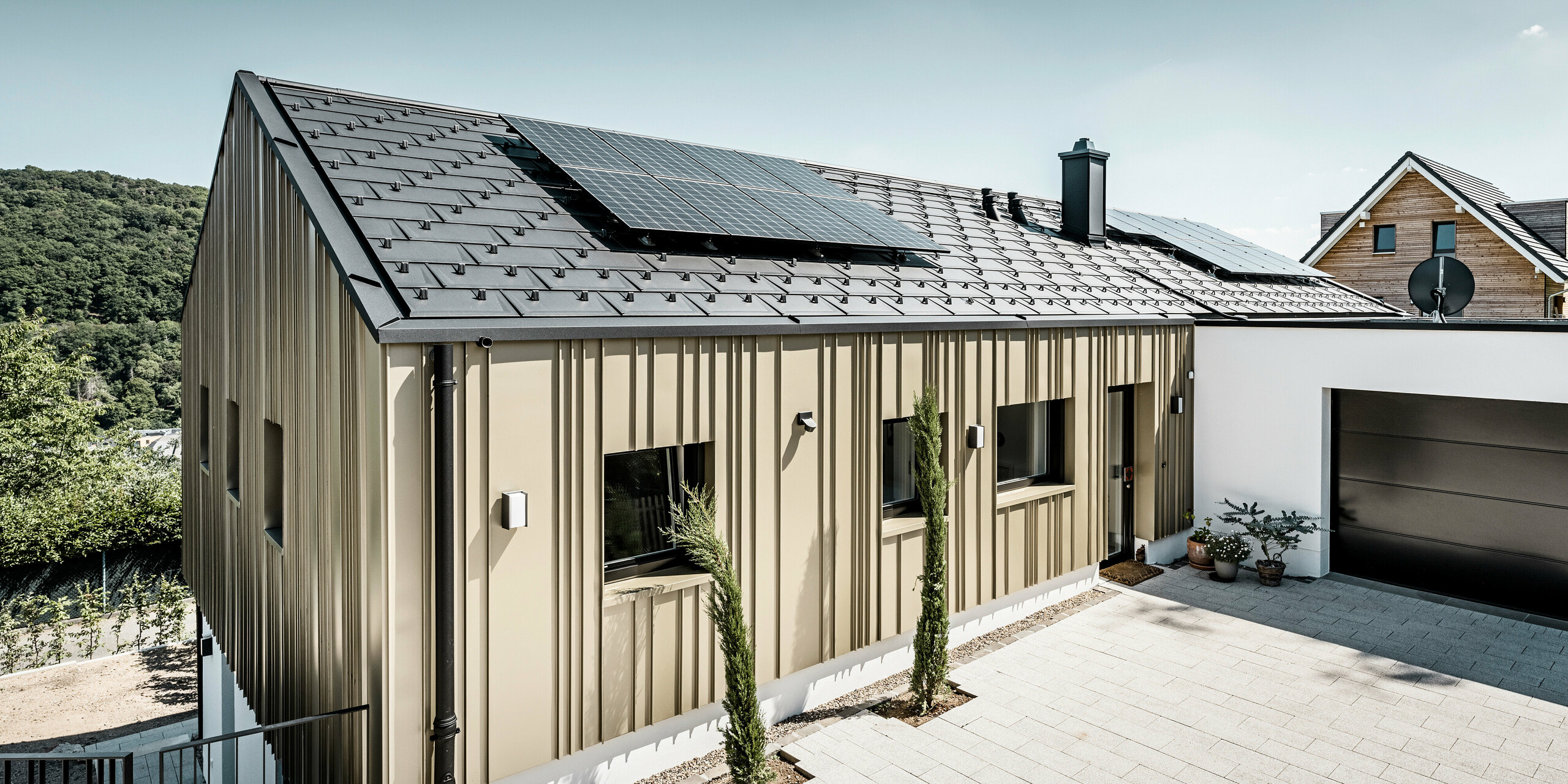 Novostavba v Bad Münstereifel byla pokryta střešním panelem PREFA R.16 v barvě P.10 antracitové. Na střeše je fotovoltaický systém. Fasáda je opláštěna hliníkovým plechem Falzonal ve světlém bronzu.