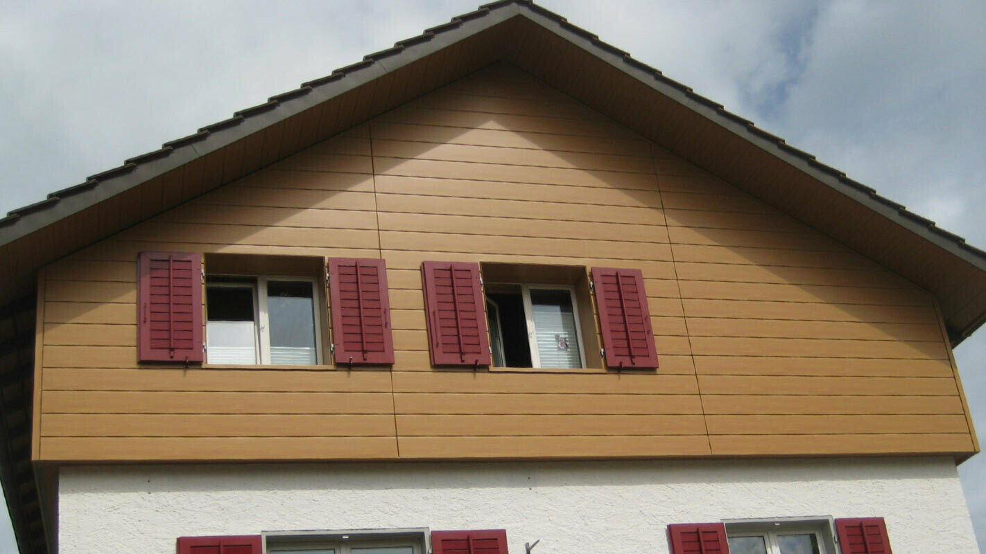 Fasáda domu s horizontálně montovanými PREFA Sidings, okna s červenými okenicemi