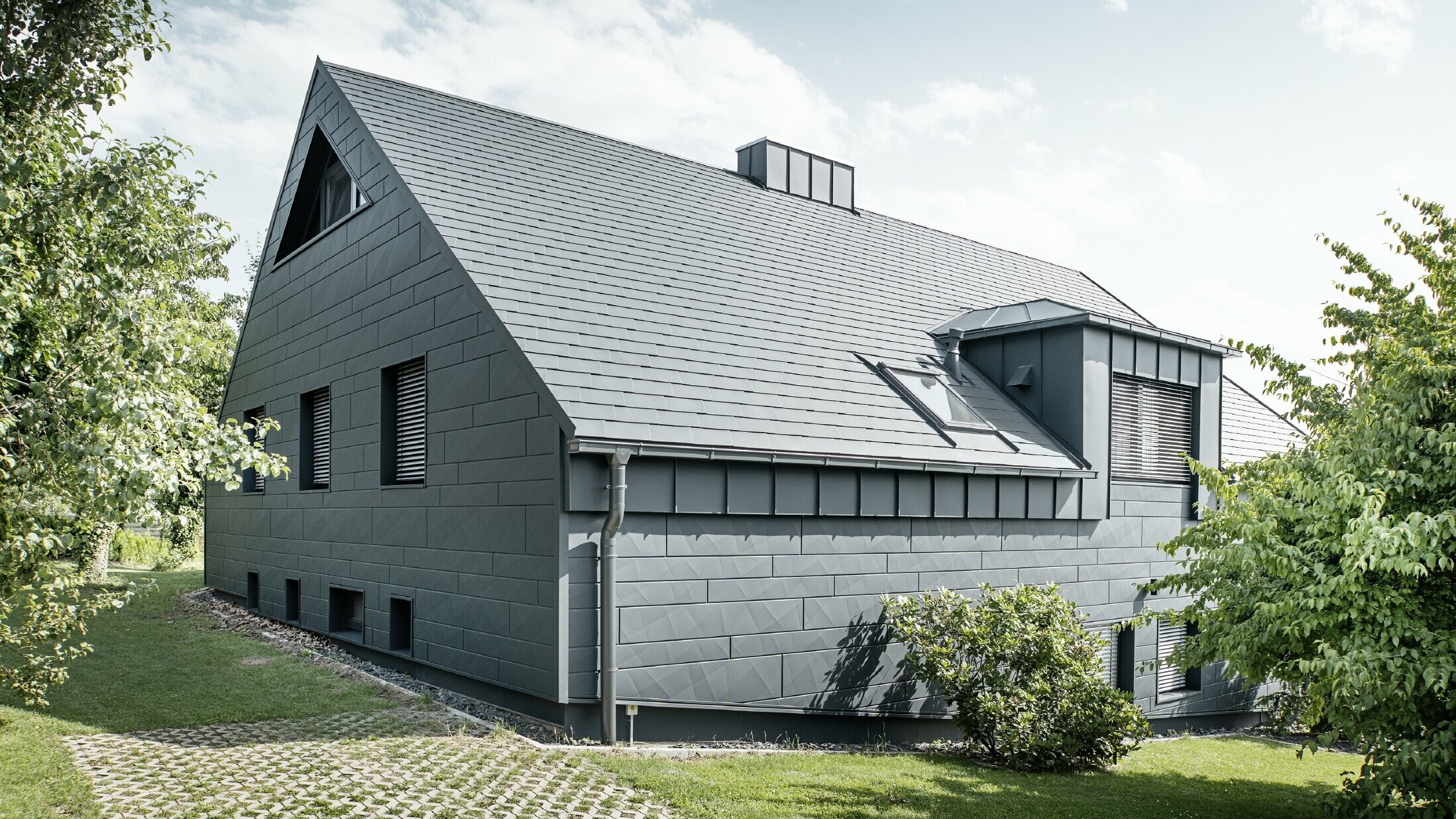 Boční pohled na dům se střechou z falcovaného šindele v barvě P.10 antracitové