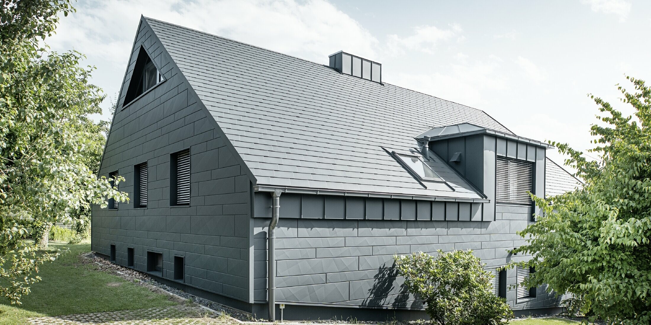 Boční pohled na dům se střechou z falcovaného šindele v barvě P.10 antracitové