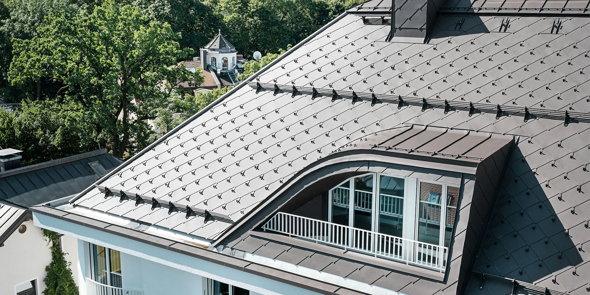 Vícegenarční dům s PREFA falcovanými šablonami 44 × 44 v hnědé barvě se sněhovými háky a sněhovými zábranami