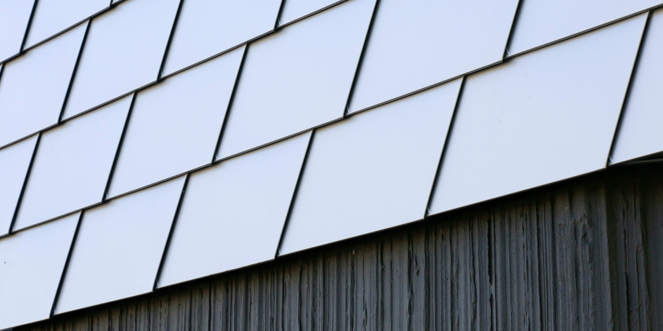 Detailní pohled na betonový základ budovy a fasádu z fasádních šindelů PREFA ve stříbrné metalíze na zdravotním středisku v Le Landreau