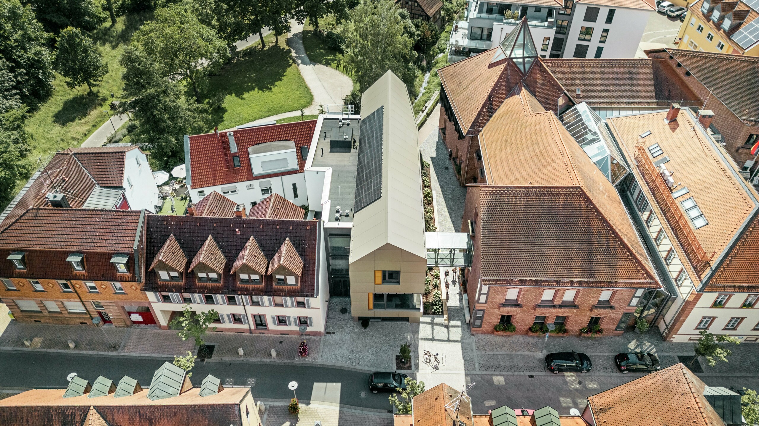 Radnice v německém Alzenau se nachází uprostřed historické městské krajiny, obklopená tradičními budovami s červenými taškovými střechami. Naproti tomu moderní radnice, jejíž fasáda je obložena hliníkovými kompozitními panely PREFABOND v elegantním bronzovém odstínu, jasně vyniká mezi sousedními klasickými budovami a harmonicky splývá s městskou krajinou.