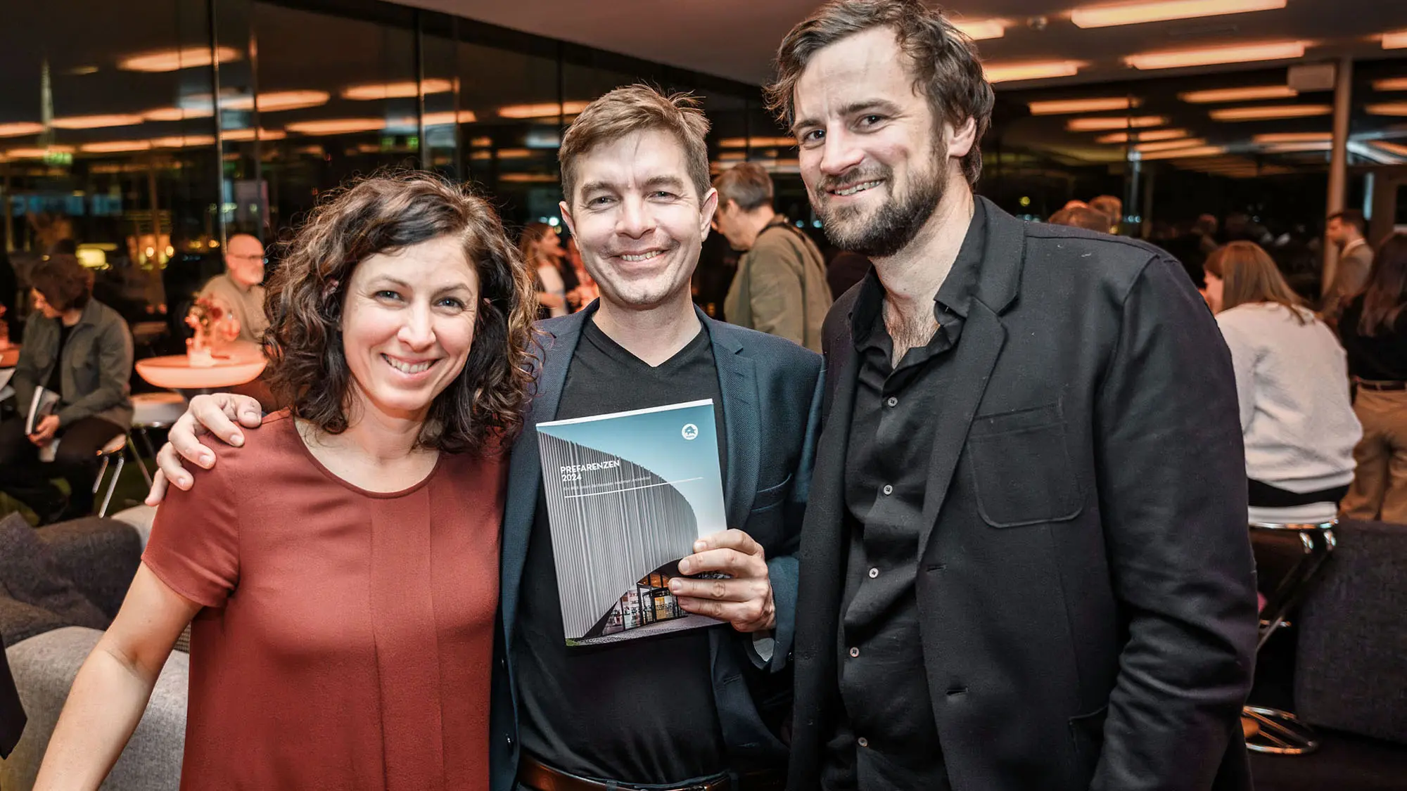 Architektin Susi Matt, Architekt Mario Dallaserra, das PREFARENZEN Buch 2024 haltend, und Architekt Benedikt Hörmann.