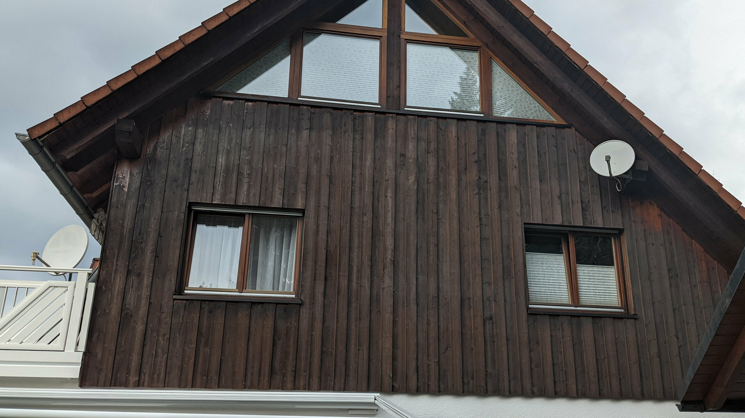 Die Holzfassade eines Gebäudes vor der Sanierung