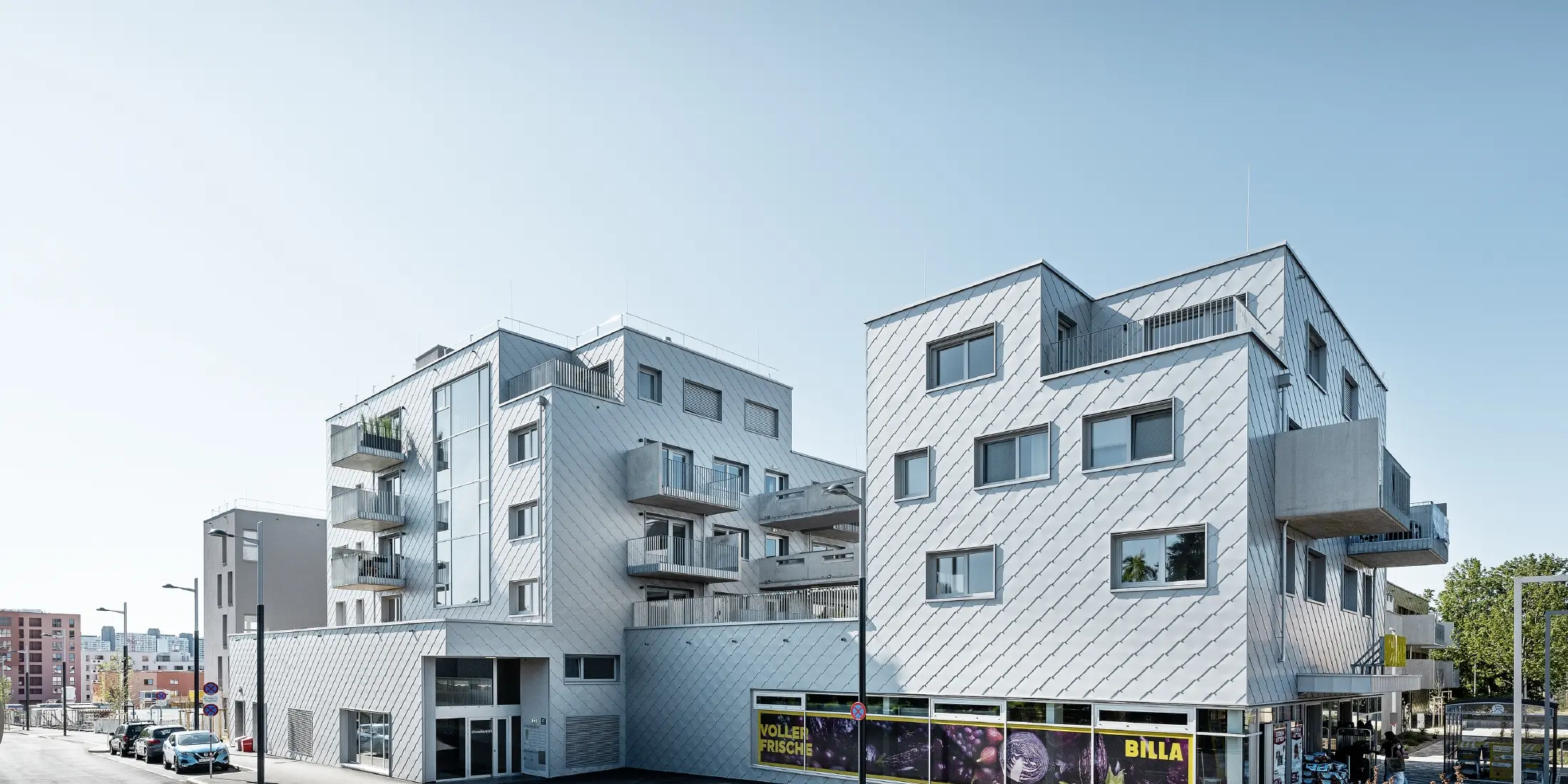 Bytové domy s plochou střechou a fasádou obloženou PREFA fasádními šablonami 44 × 44 v barvě stříbrná metalíza