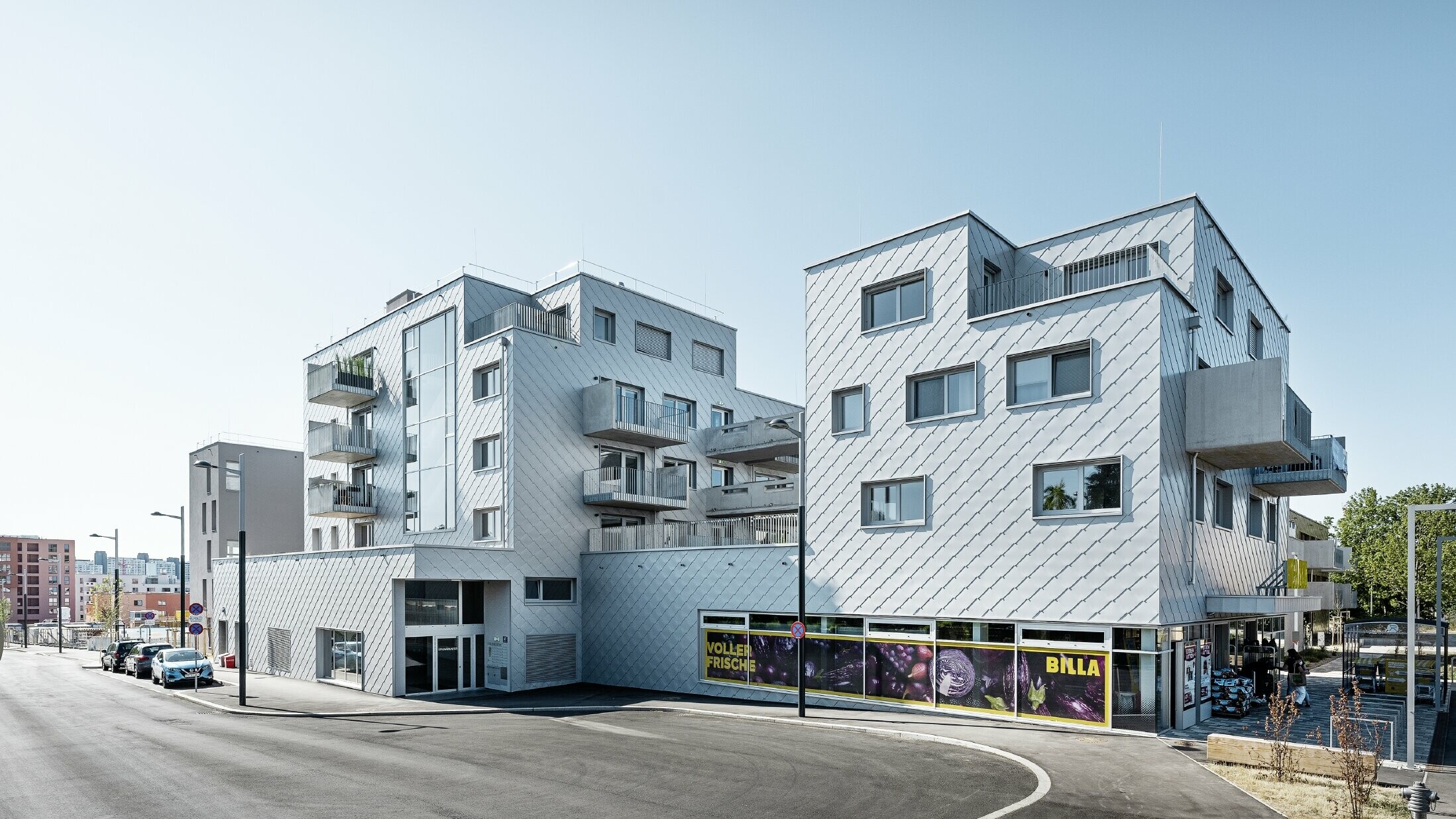 Obytný komplex s plochou střechou obložený fasádními šablonami v barvě stříbrné metalízy