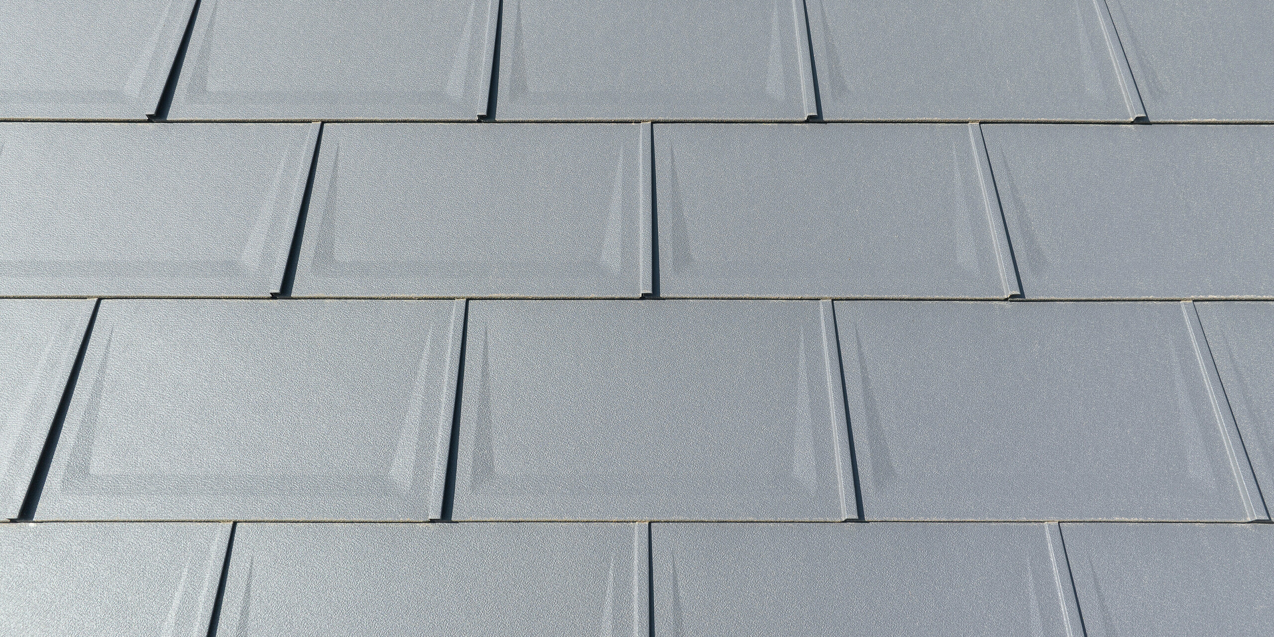 Pohled zblízka na střešní panel R.16 v barvě P.10 tmavě šedé v povrchové úpravě stucco namontovaný v pravidelných řadách