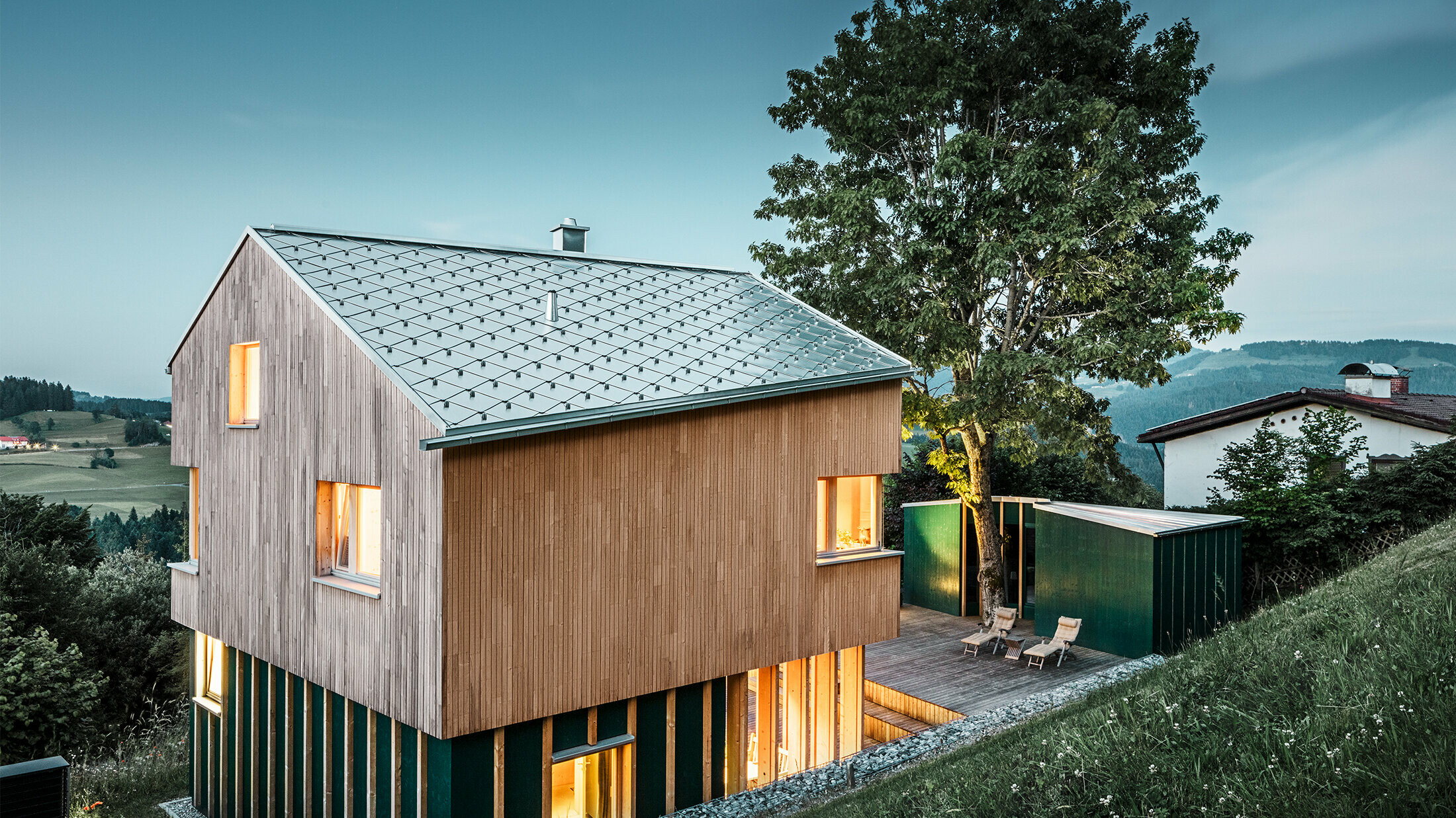 Nově postavený rodinný dům s dřevěnou fasádou a falcovanými šablonami PREFA v přírodním hliníku