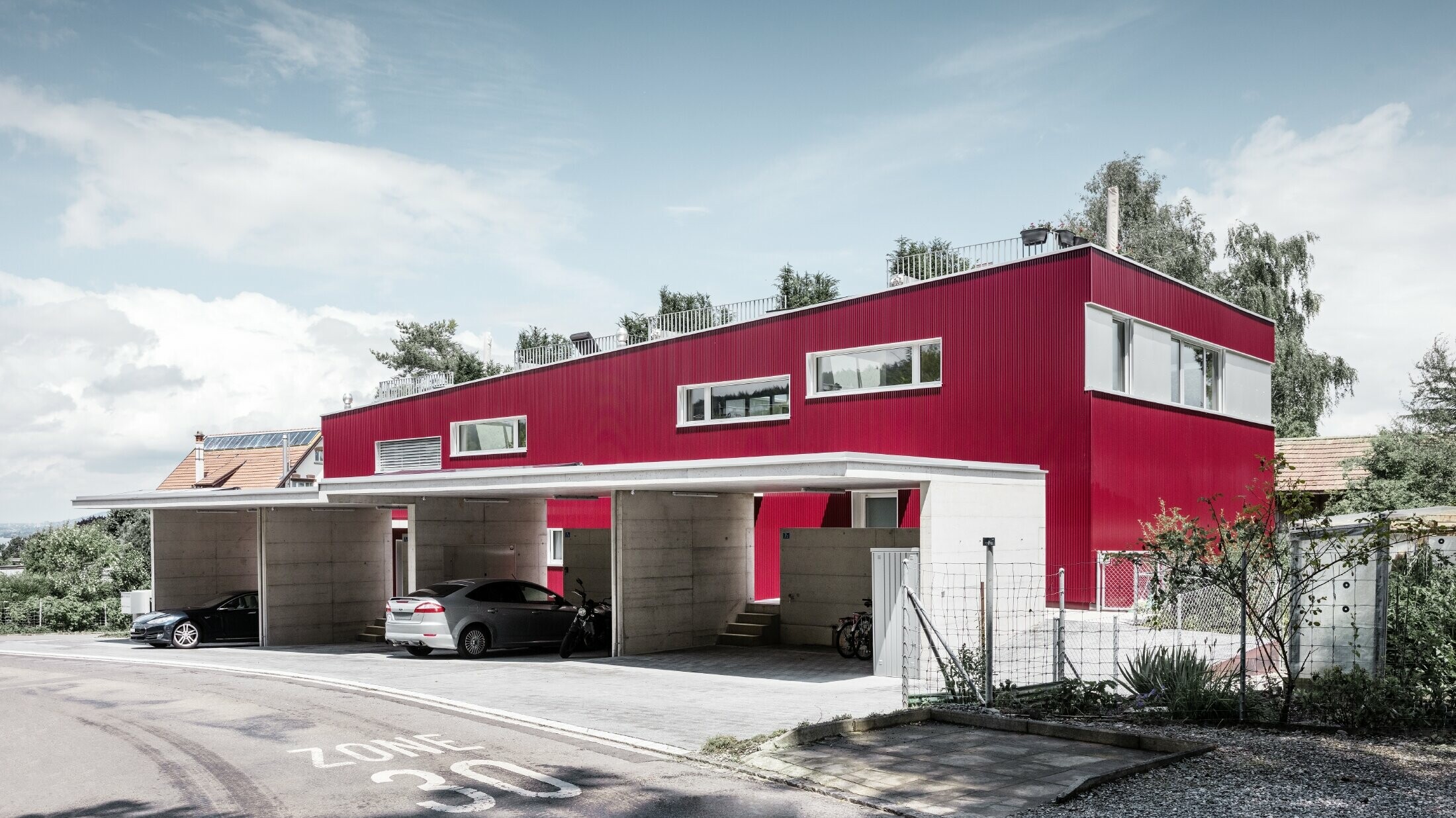 Nově postavené domy zdobí zářivě červená fasáda z lisovaných profilů PROFILWELLE