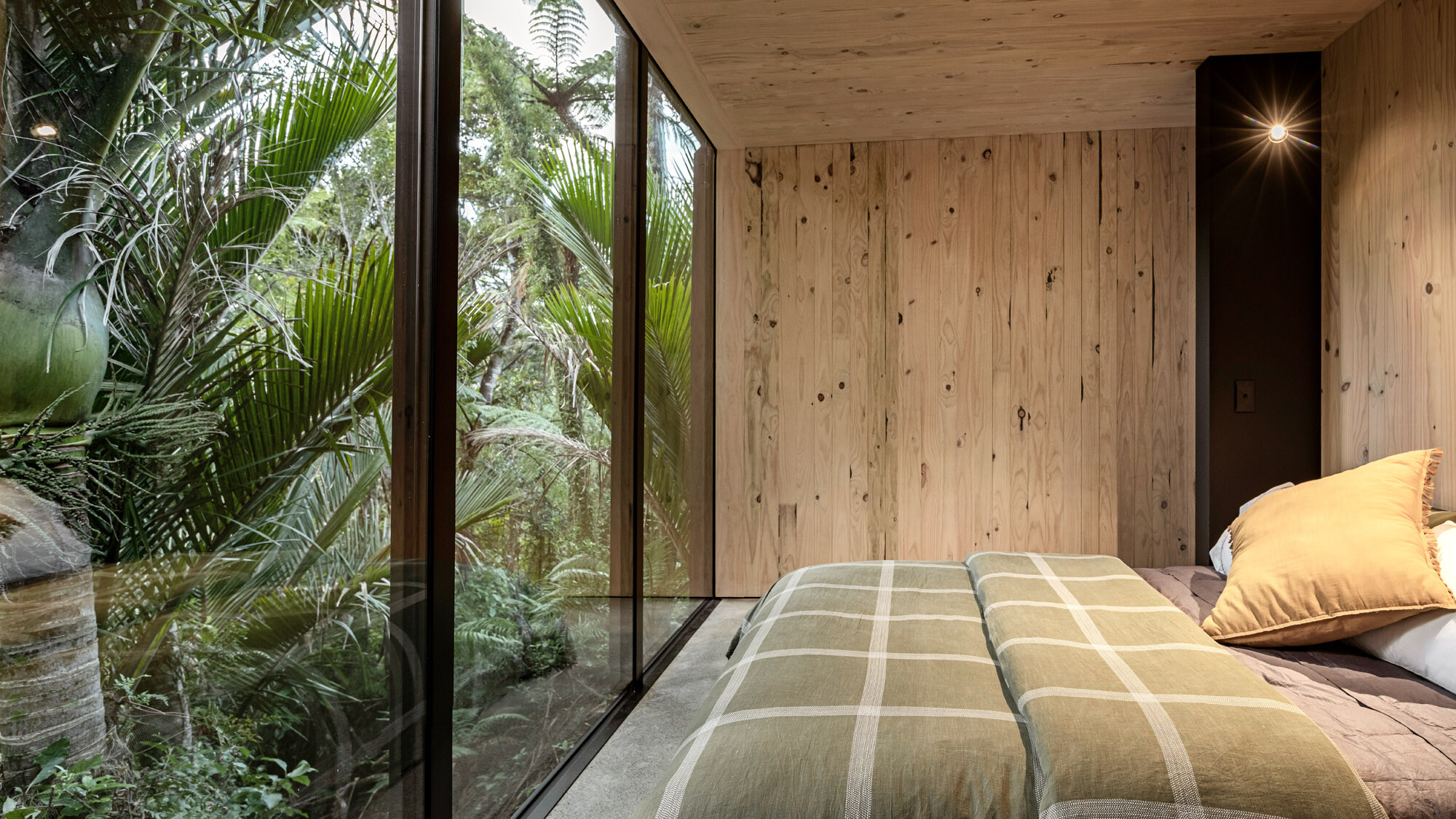 Ložnice s oknem od podlahy ke stropu, která je přímo spojena s džunglí.