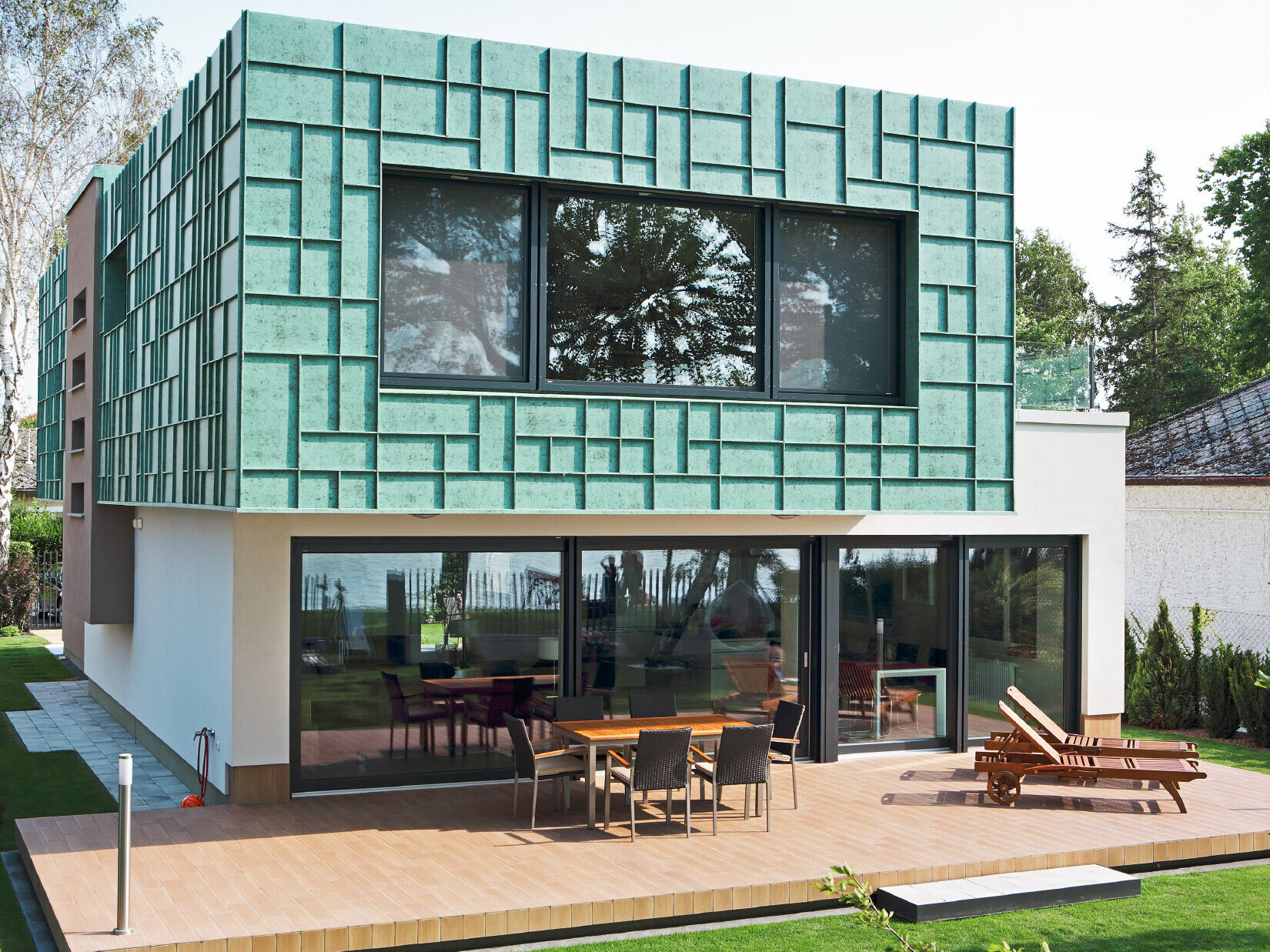 Moderní rodinný domek s fasádou odolnou proti větru, obloženou prvky PREFALZ v barvě P10 zelená patina.