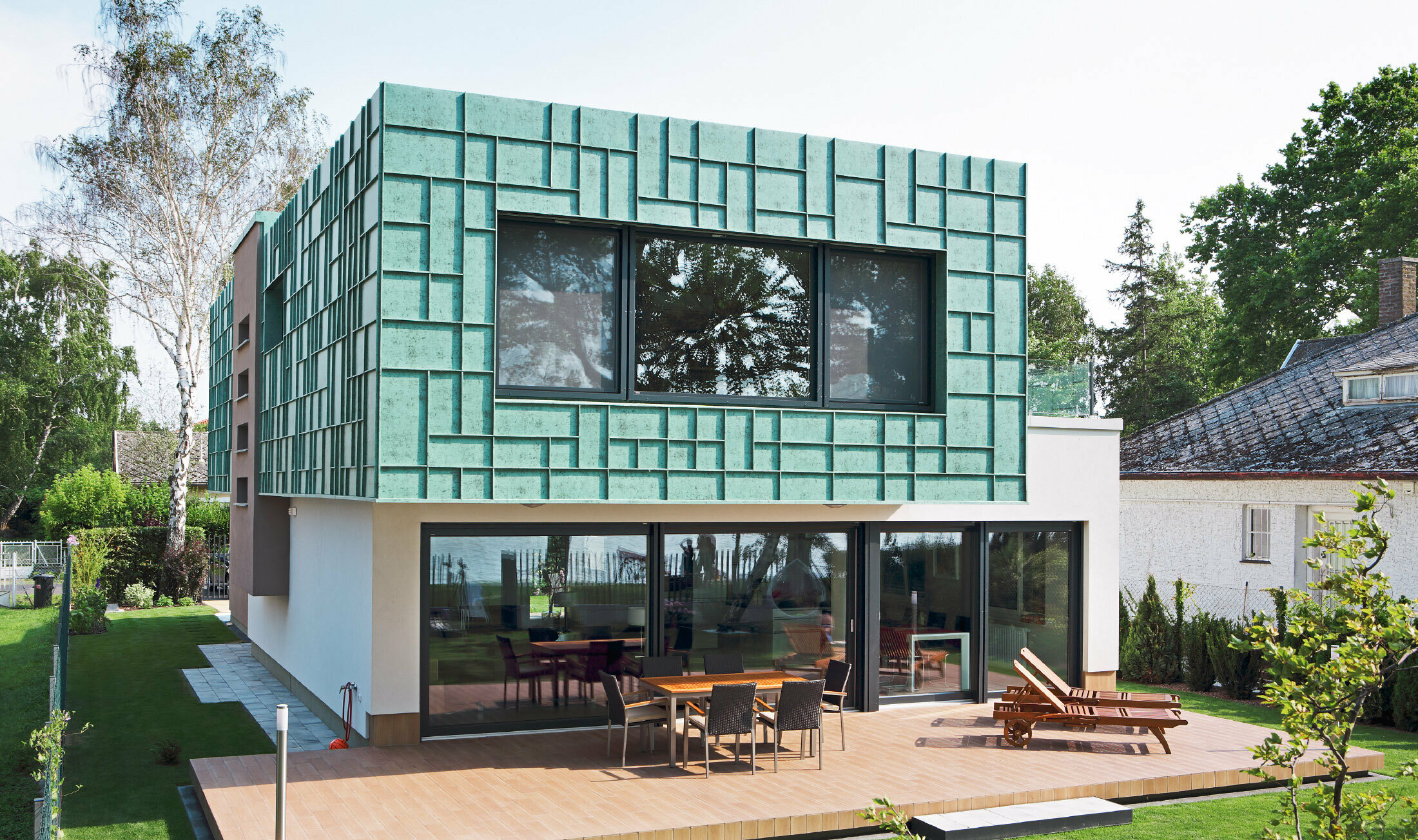 Moderní rodinný domek s fasádou odolnou proti větru, obloženou prvky PREFALZ v barvě P10 zelená patina.