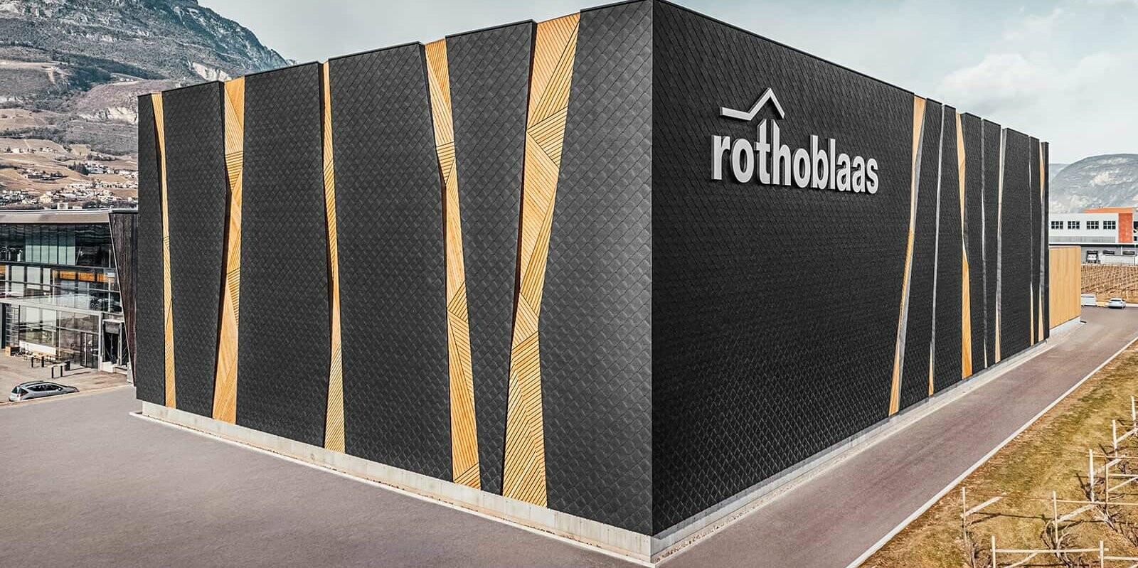 Průmyslový objekt - budova centrálního skladu Rothoblaas obložený fasádní šablonou PREFA 44 x 44 v barvě P.10 černá.