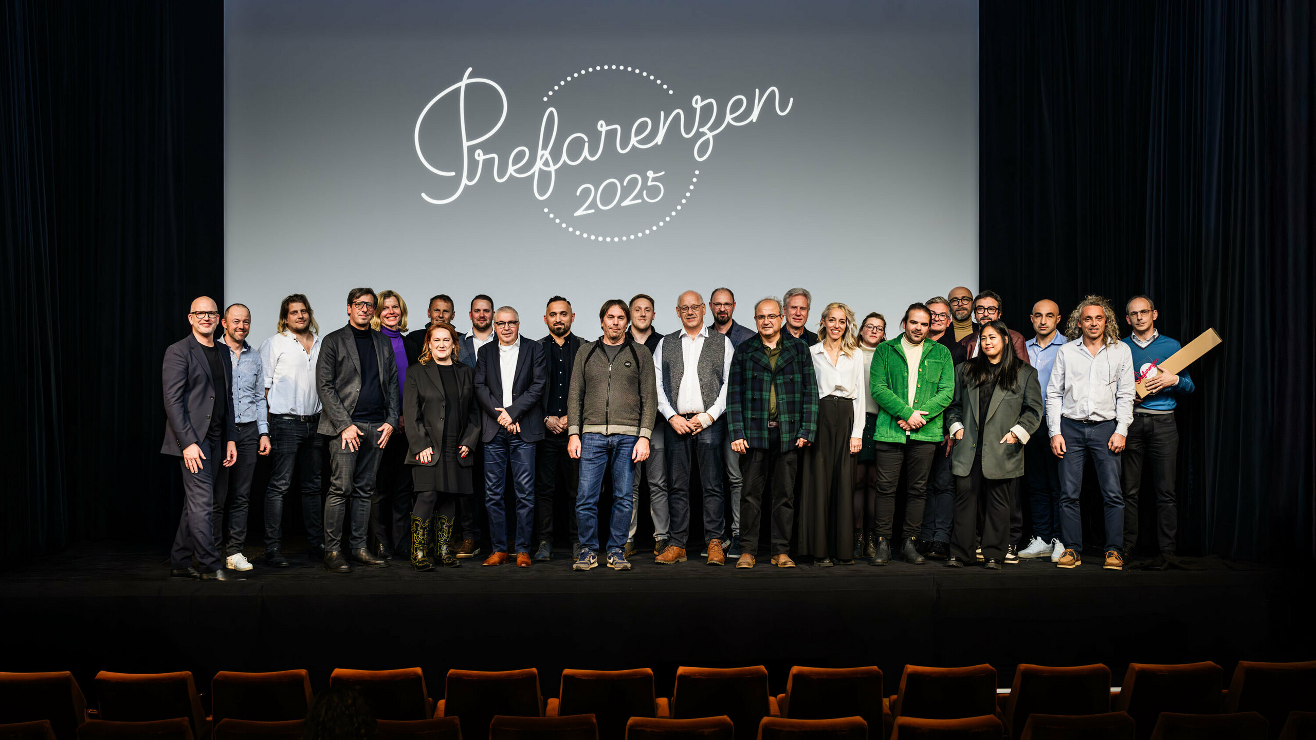 Skupinová fotografie na premiéře PREFARENZEN 2025 ve vídeňském městském kině: Jürgen Jungmair, marketingový manažer PREFA s účastníky a hosty před logem akce „Prefarenzen 2025“ na obrazovce. Účastníci zde zastupují architekturu, plánování, realizaci a média z celé Evropy.