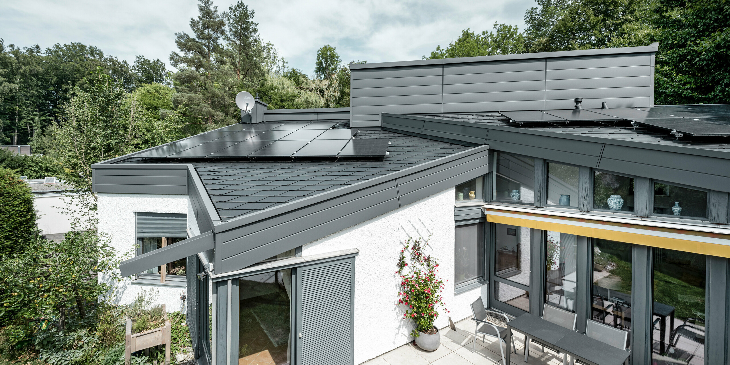 Ein Einfamilienhaus, das mit PREFA Dachschindeln DS.19 in schwarz eingedeckt wurde. Für Teile der Fassade wurden PREFA Sidings in P.10 dunkelgrau verwendet. 