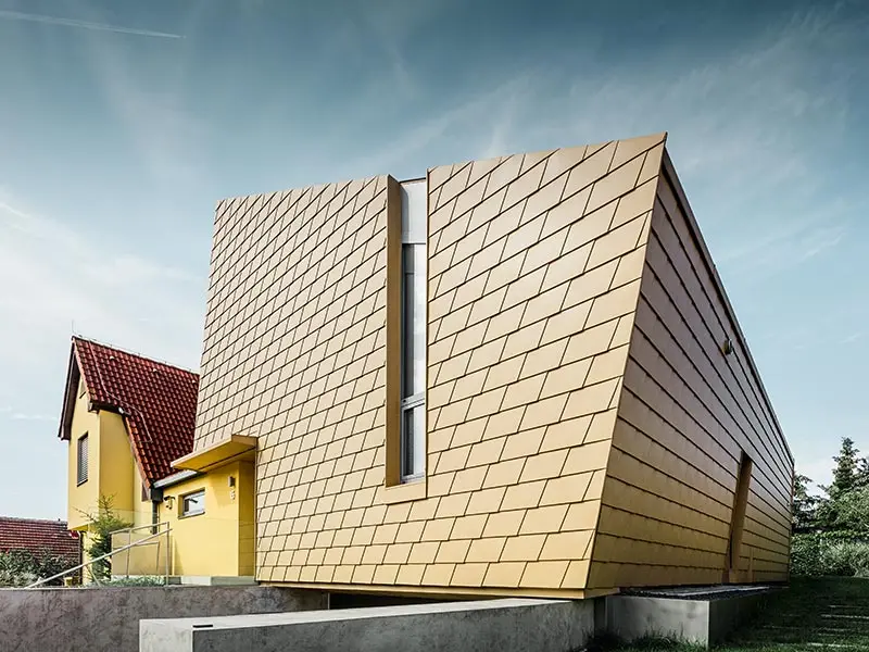 Velmi moderní přístavba rodinného domu, která je opláštěná hliníkovou fasádou PREFA v podobě hliníkových šindelů v barvě P.10 pískové