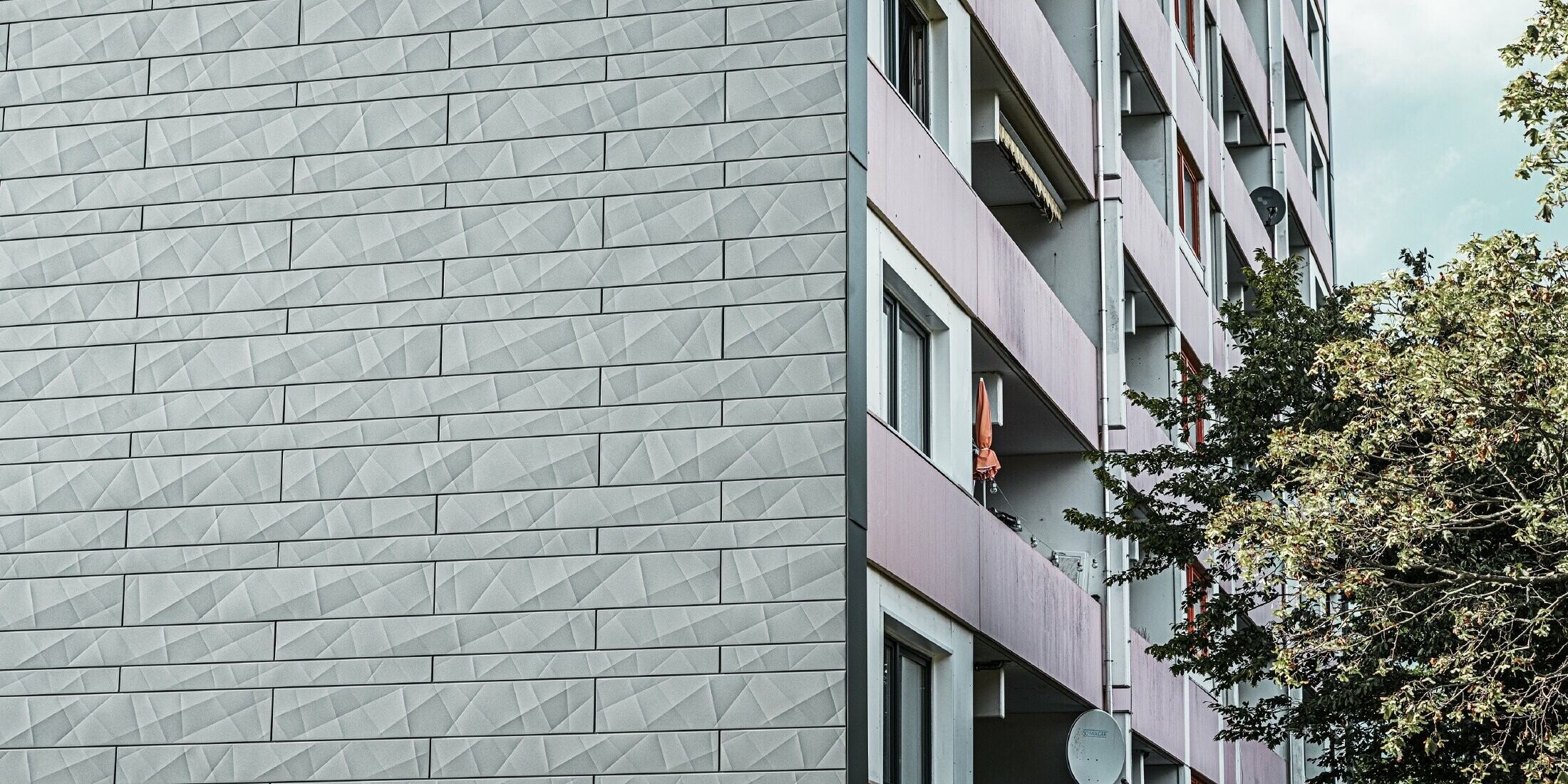 Pohled na fasádní lamely Siding.X v barvě P.10 světle šedé na ploše fasády výškového domu