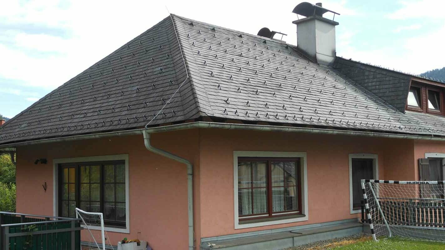 Valbová střecha s trapézovým vikýřem před sanací za použití PREFA falcovaných střešních šindelů