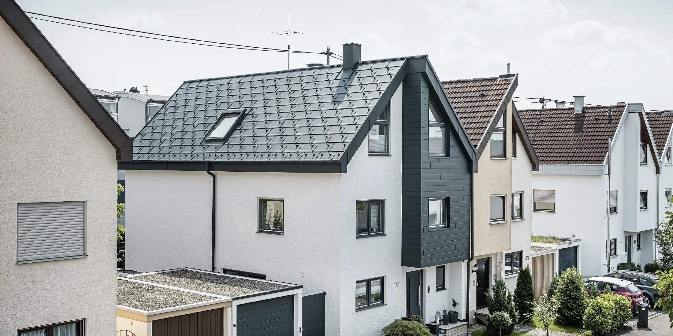 Polovina dvojdomu již byla zrekonstruována – s novou bílou omítkovou fasádou, kombinovanou s PREFA fasádními lamelami Siding.X v antracitové barvě. Střecha byla pokryta PREFA střešním panelem R.16. Odvodnění střechy je řešeno PREFA hranatým žlabem s kruhovým svodem.
