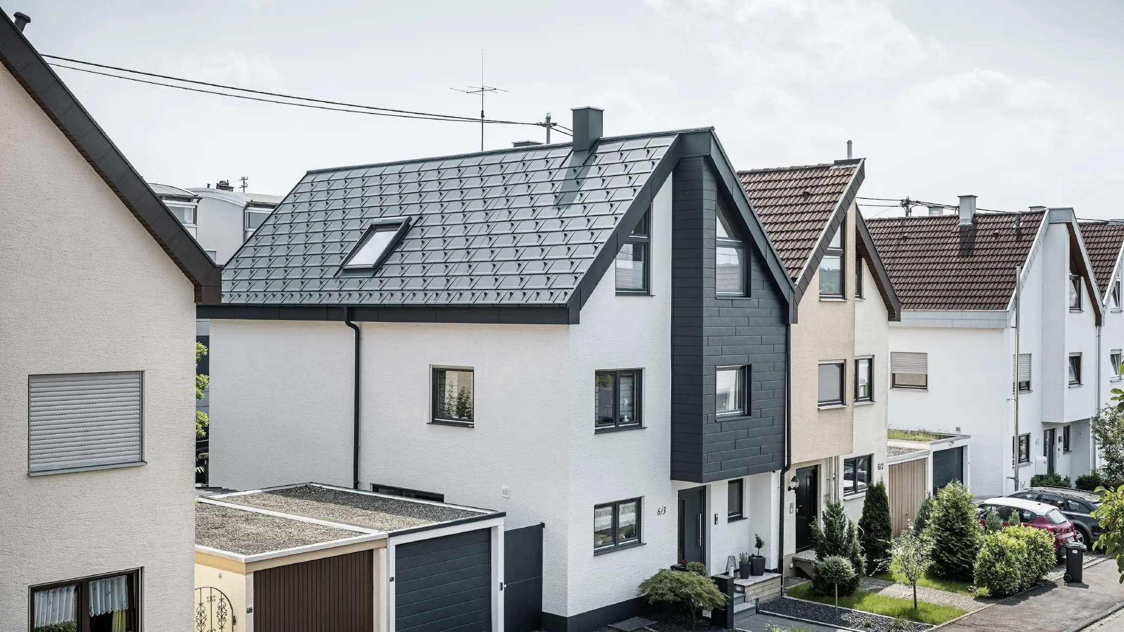 Polovina dvojdomu již byla zrekonstruována – s novou bílou omítkovou fasádou, kombinovanou s PREFA fasádními lamelami Siding.X v antracitové barvě. Střecha byla pokryta PREFA střešním panelem R.16. Odvodnění střechy je řešeno PREFA hranatým žlabem s kruhovým svodem.