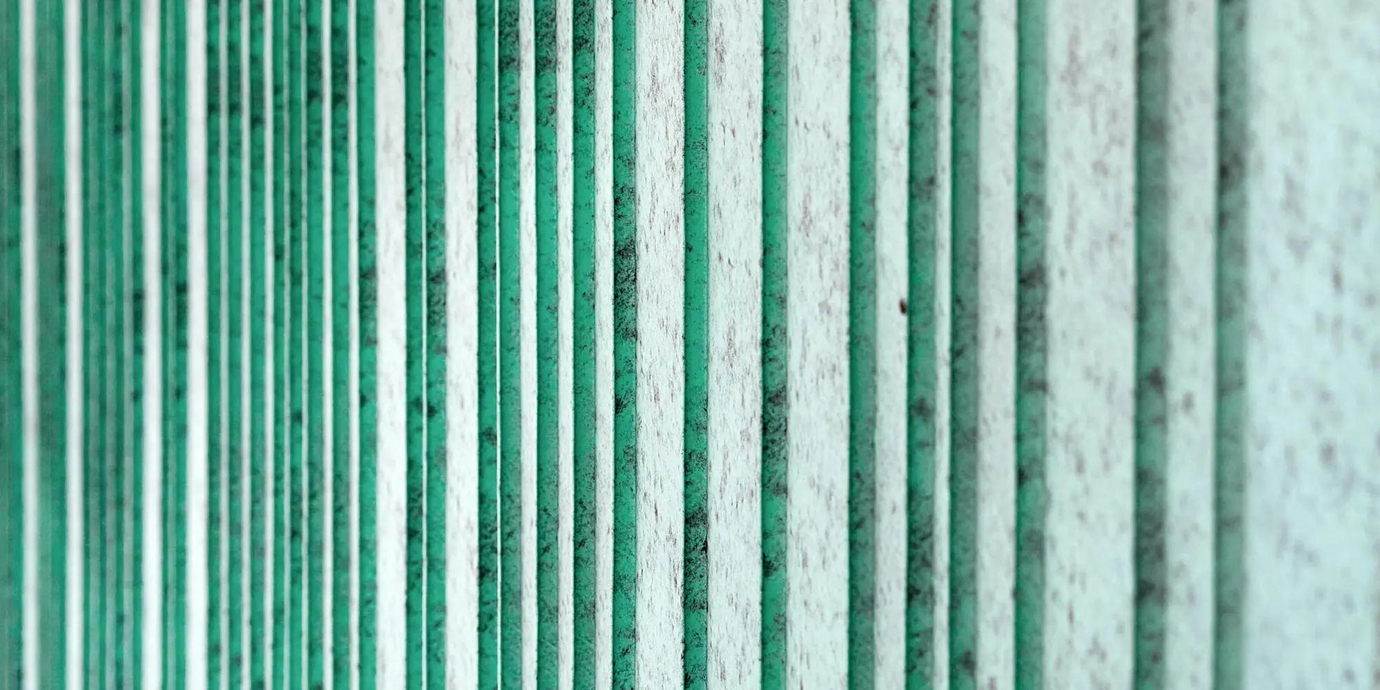 Detailní pohled na hliníkovou fasádu PREFALZ v barvě P.10 patině zelené. Fasáda je rytmizována šáry různých šířek. Barva vytváří melírovaný vzhled.