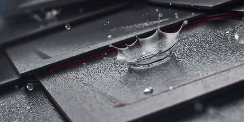 Detailní záběr PREFA střešní šablony s kapkami vody na povrchu. Krytina má povrchovu úpravu stucco a antracitovou barvu. 