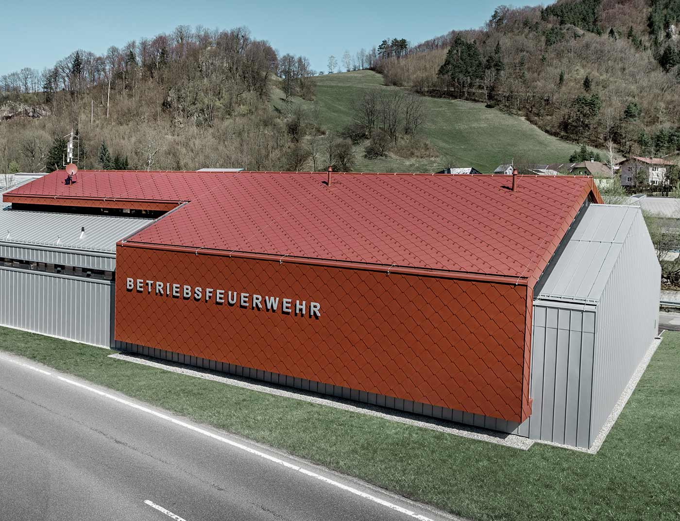 PREFA střešní šablona 44 × 44 tmavě červená - reference Nová zbrojnice hasičského sboru firmy PREFA a Neuman Aluminium byla opláštěna novou střešní a fasádní šablonou 44 × 44 v barvě tmavě červená P.10 a hliníkovým plechem Prefalz v provedení stříbrná metalíza.